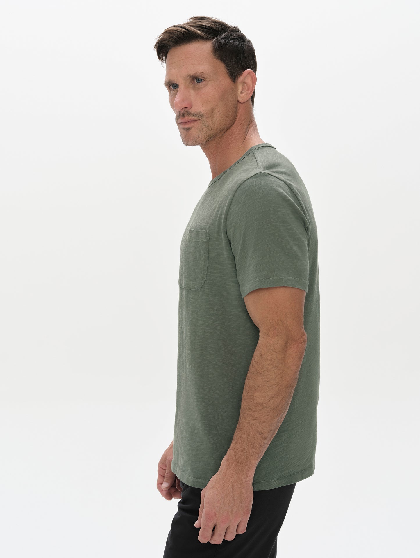 Side profile, upper-body view of man wearing the Slub Pocket Tee 2.0 in Gunmetal from AETHER Apparel.