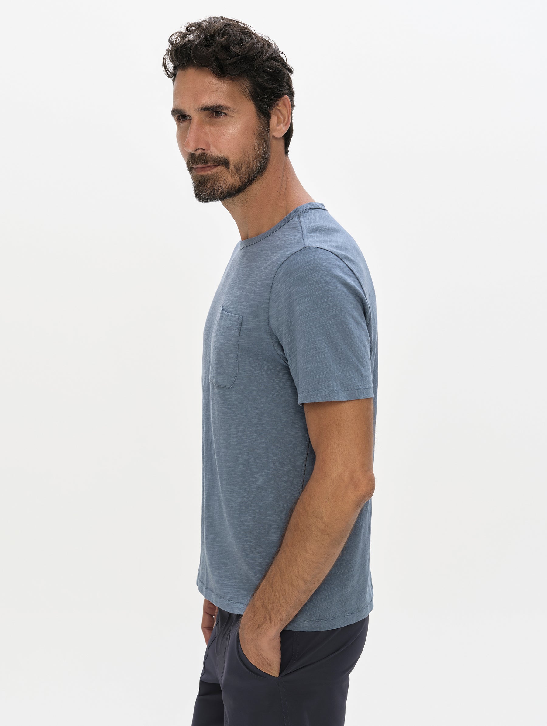 Side profile, upper-body view of man wearing the Slub Pocket Tee 2.0 in Portal Blue from AETHER Apparel.