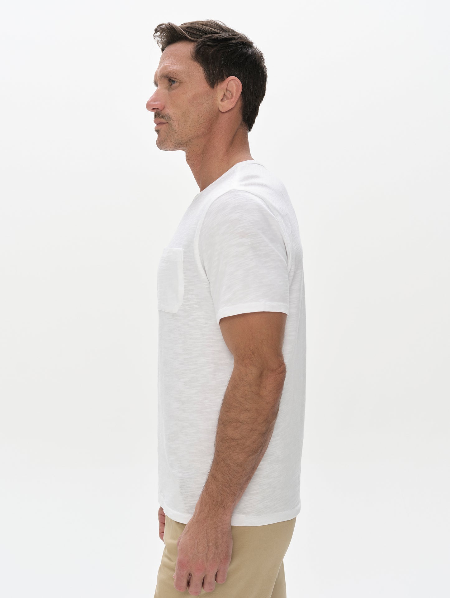 Side profile, upper-body view of man wearing Slub Pocket Tee 2.0 in White from AETHER Apparel.