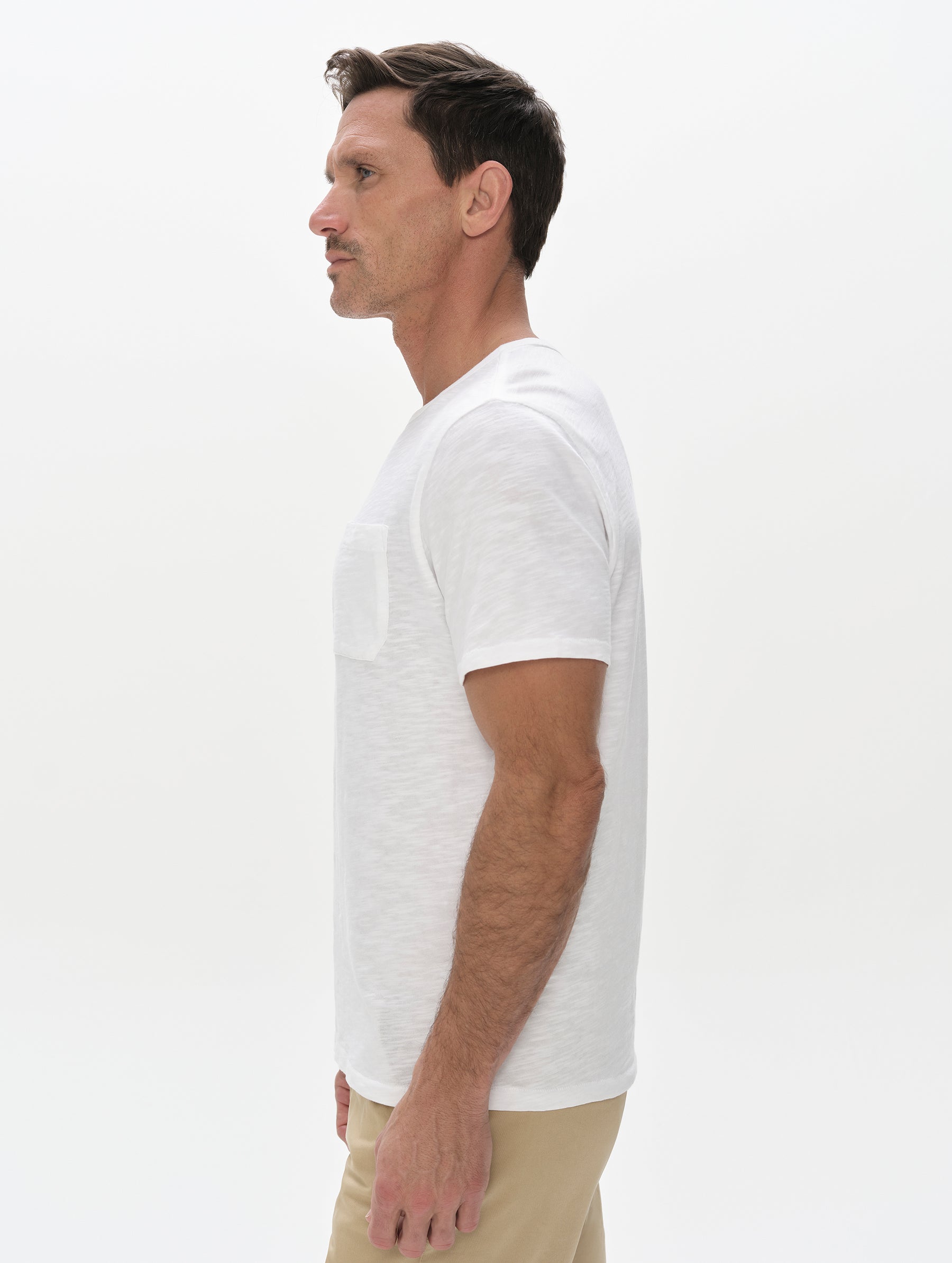 Side profile, upper-body view of man wearing Slub Pocket Tee 2.0 in White from AETHER Apparel.