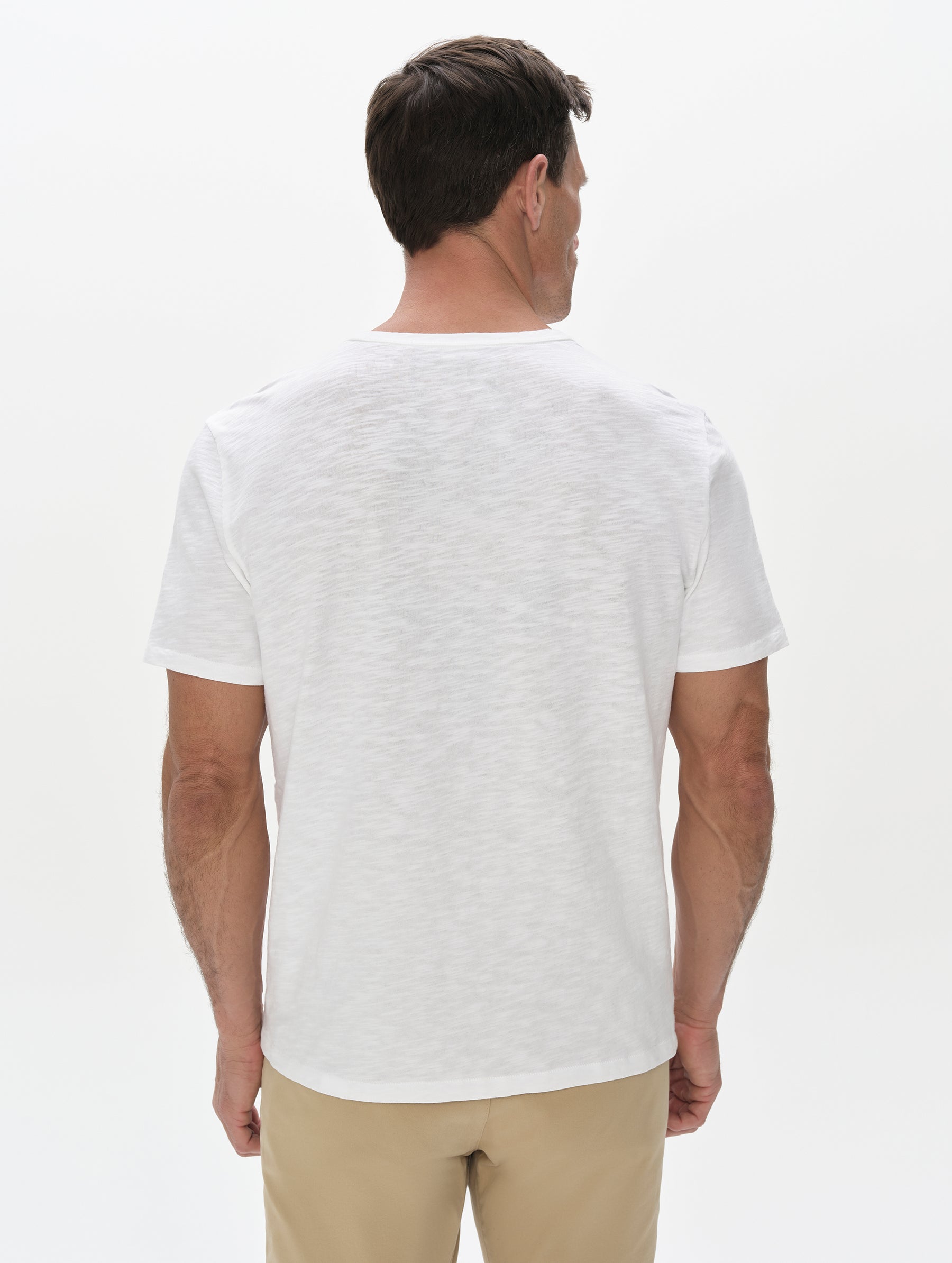 Rear, upper-body view of man wearing Slub Pocket Tee 2.0 in White from AETHER Apparel.
