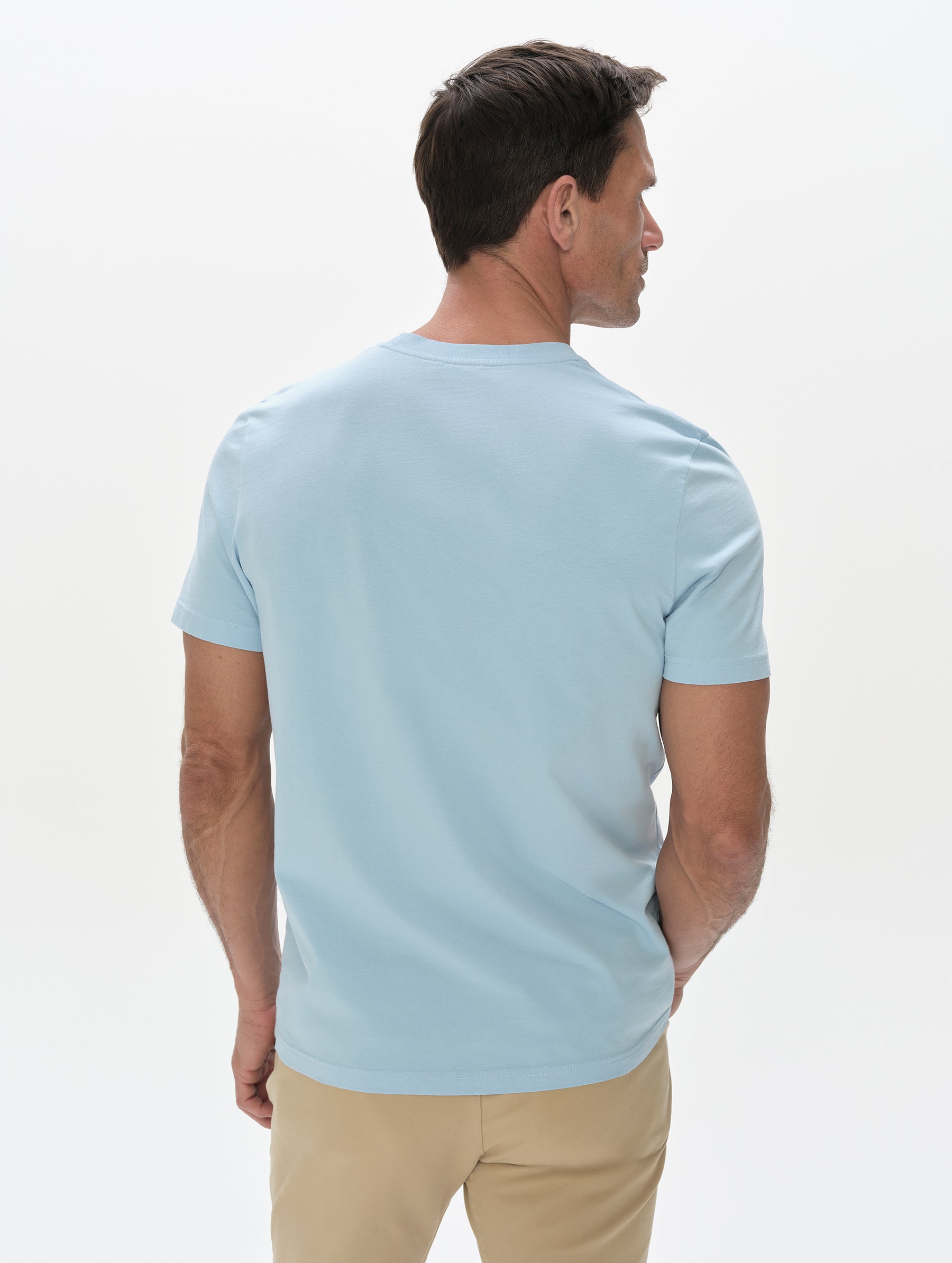 Rear, upper-body view of man wearing the Standard Tee in Cloud Blue from AETHER Apparel.