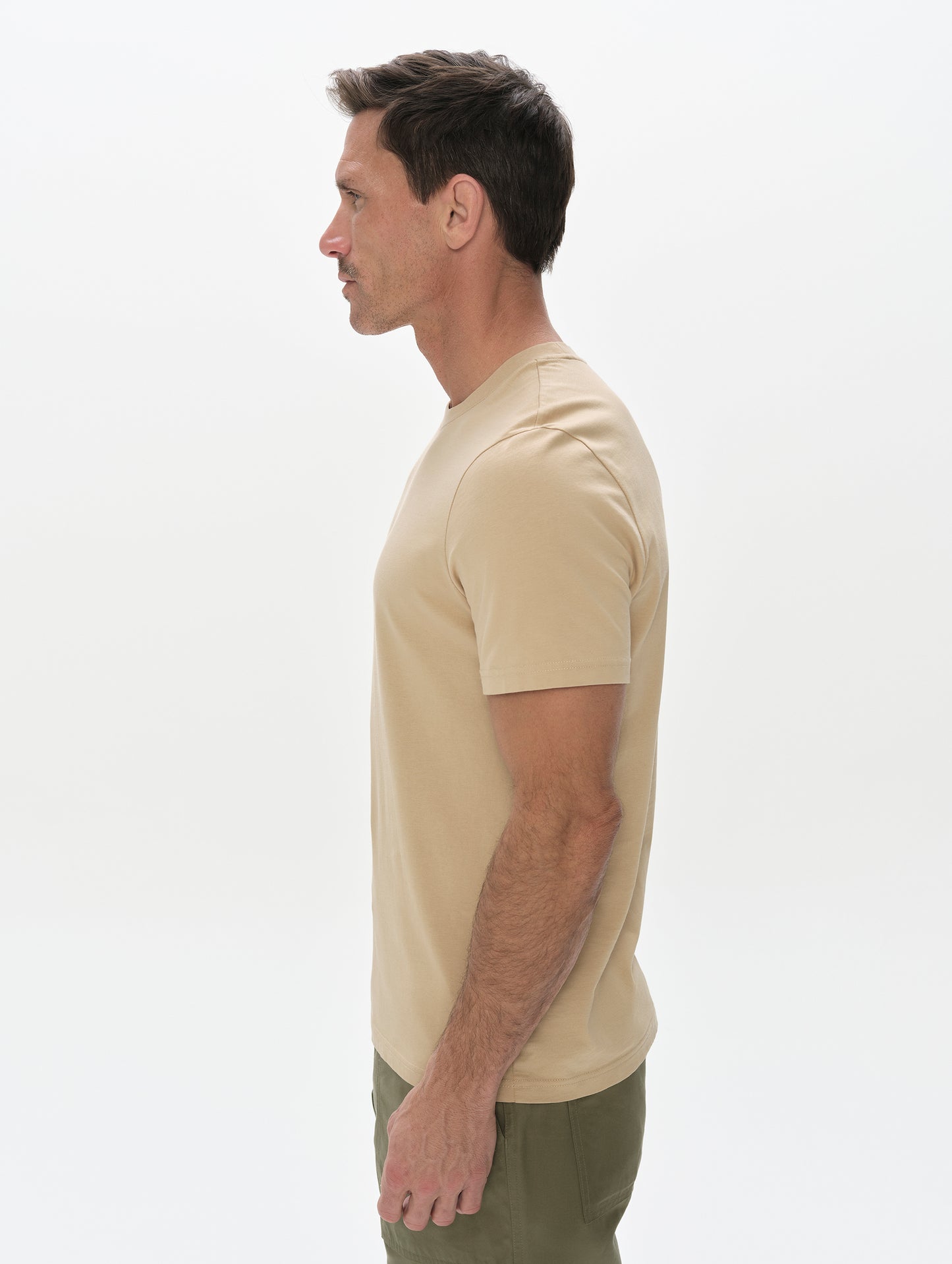 Side profile, upper-body view of man wearing the Standard Tee in Desert Tan from AETHER Apparel.