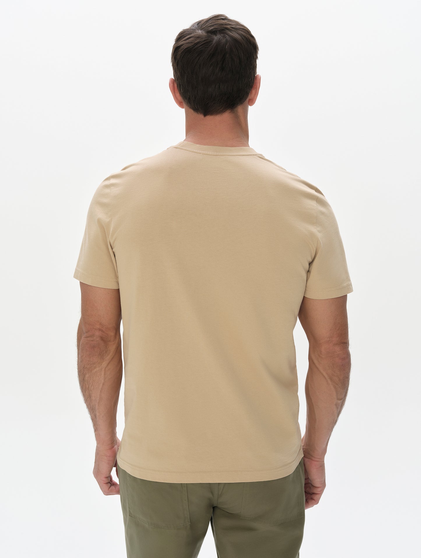 Rear, upper-body view of man wearing the Standard Tee in Desert Tan from AETHER Apparel.