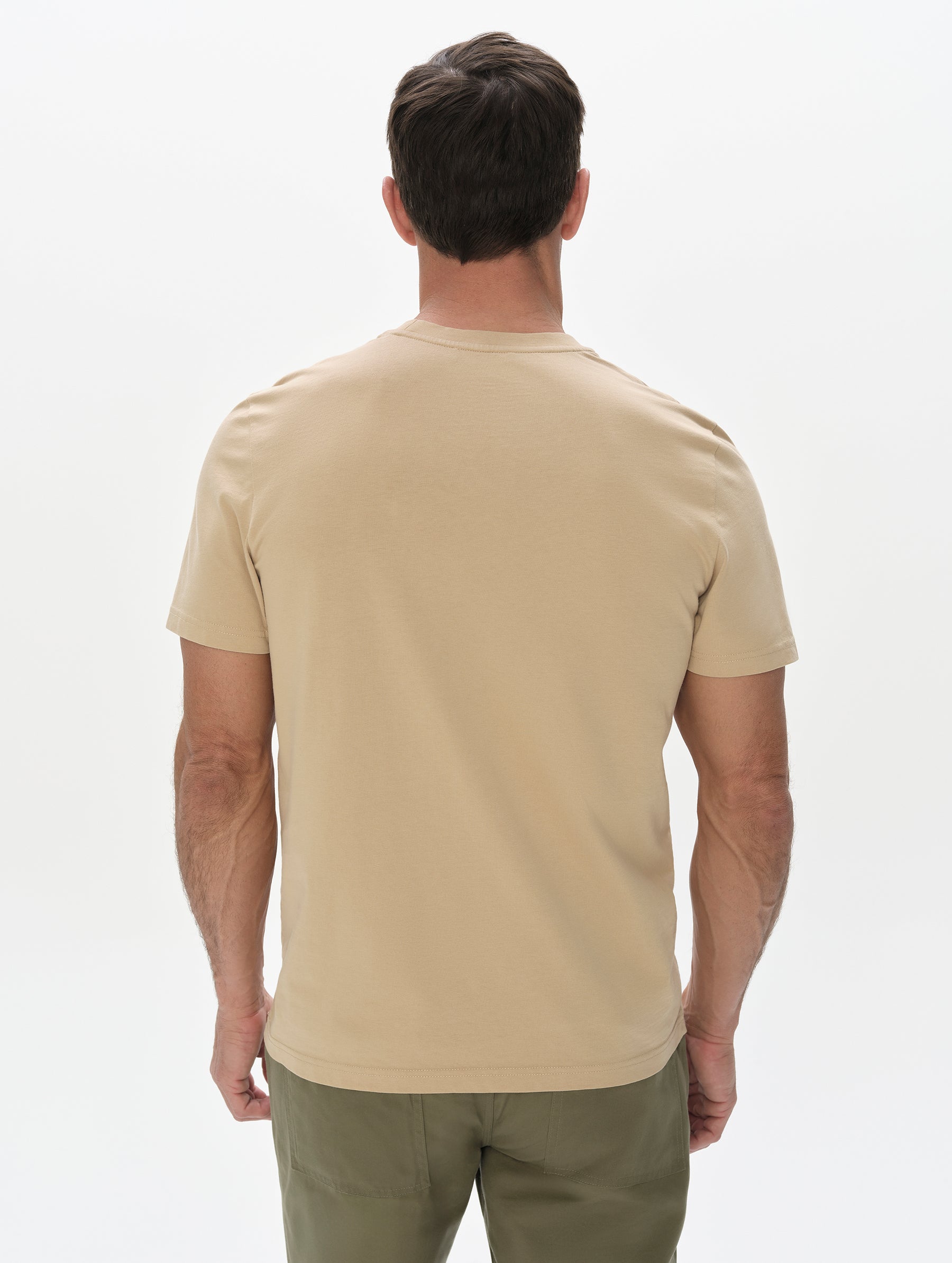 Rear, upper-body view of man wearing the Standard Tee in Desert Tan from AETHER Apparel.