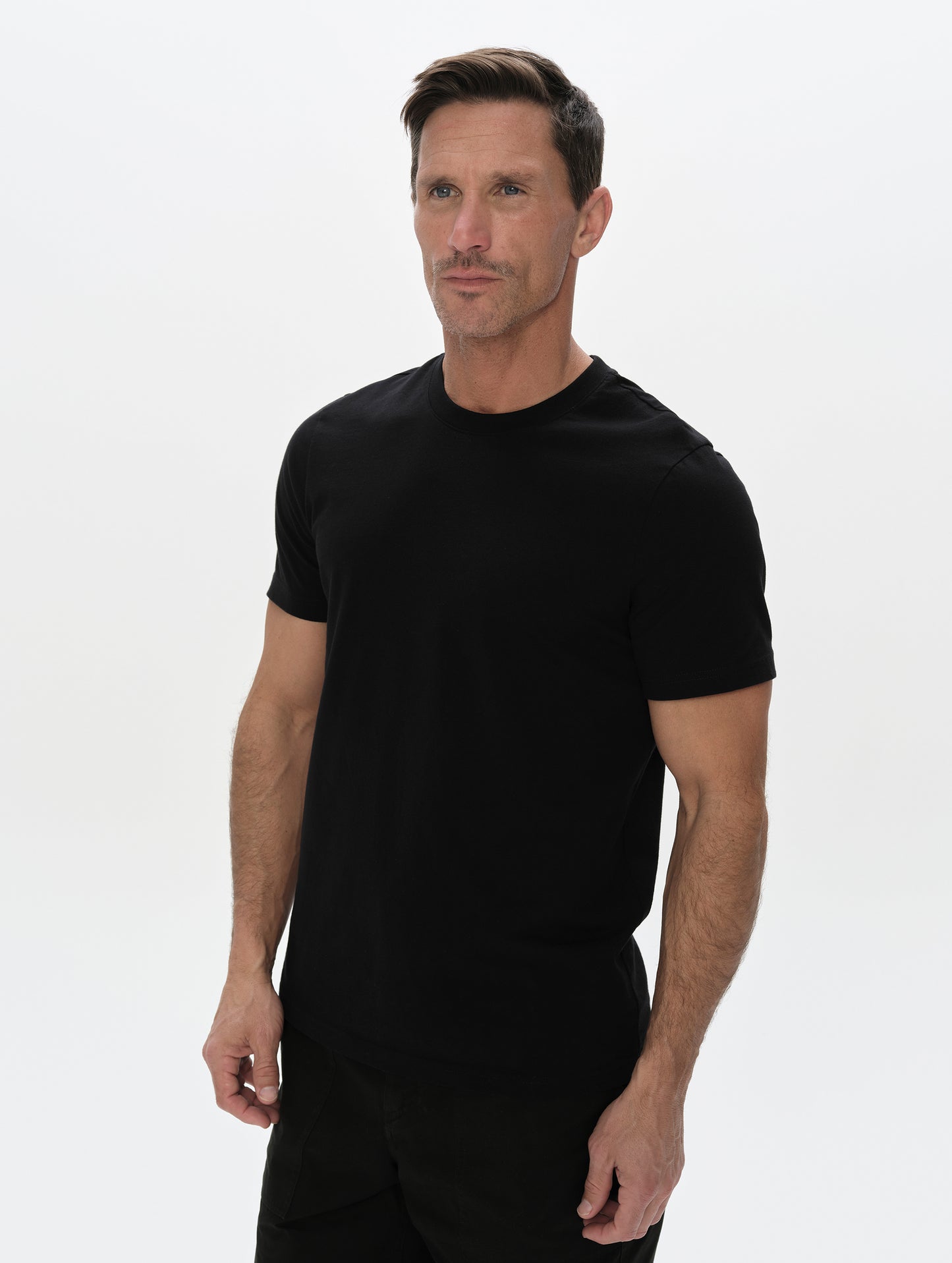 Front, upper-body view of man wearing the Standard Tee in Onyx Black from AETHER Apparel.