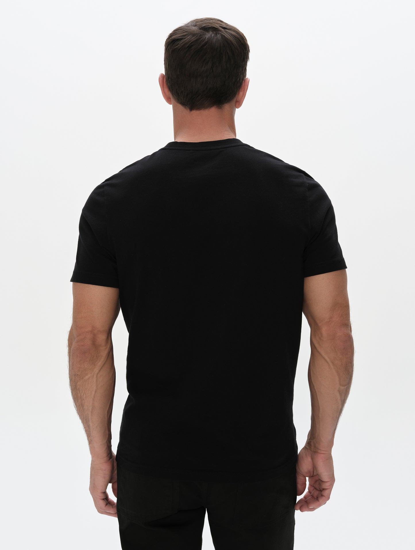 Rear, upper-body view of man wearing the Standard Tee in Onyx Black from AETHER Apparel.