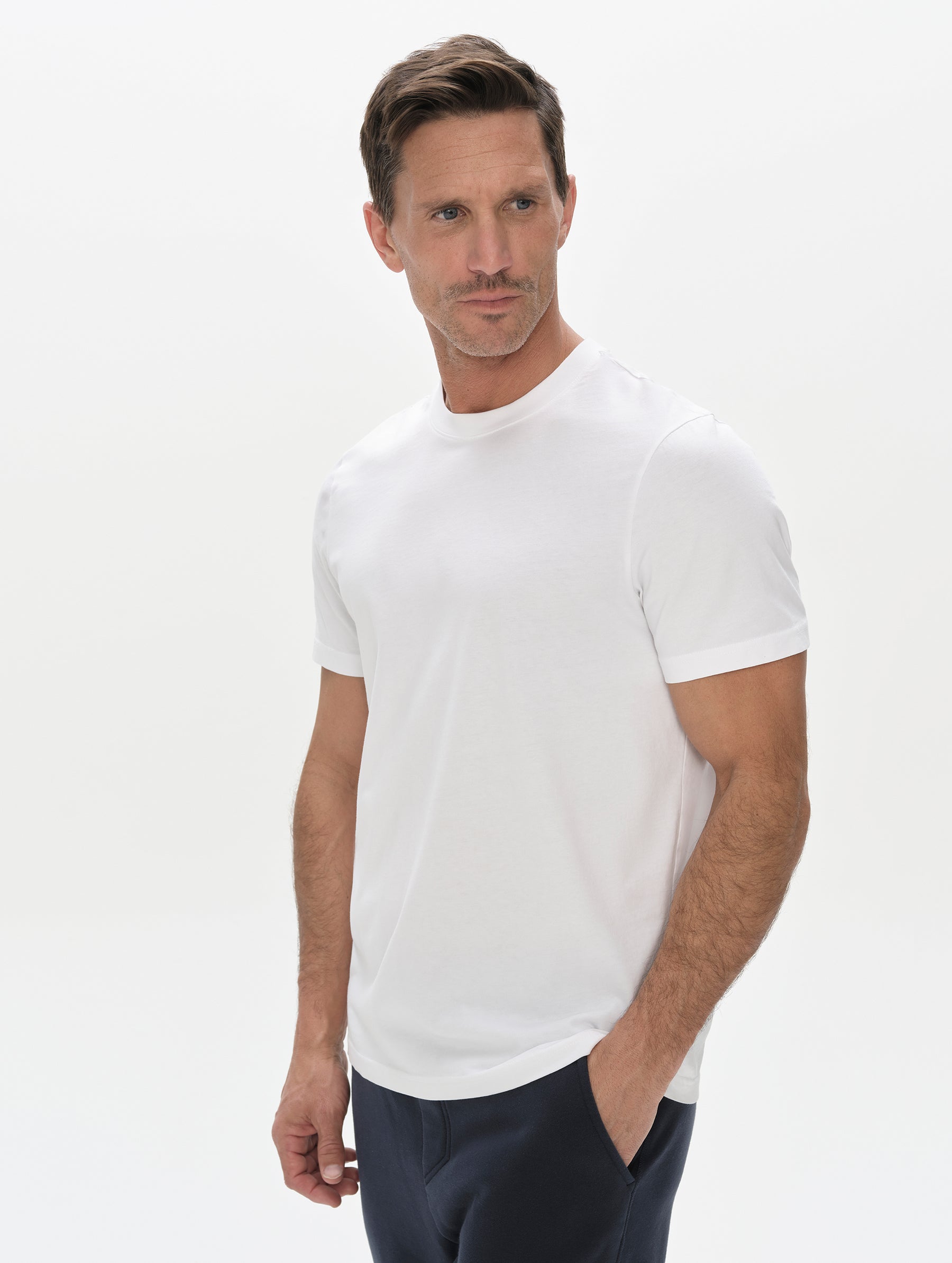 Front, upper-body view of man wearing the Standard Tee in White from AETHER Apparel.