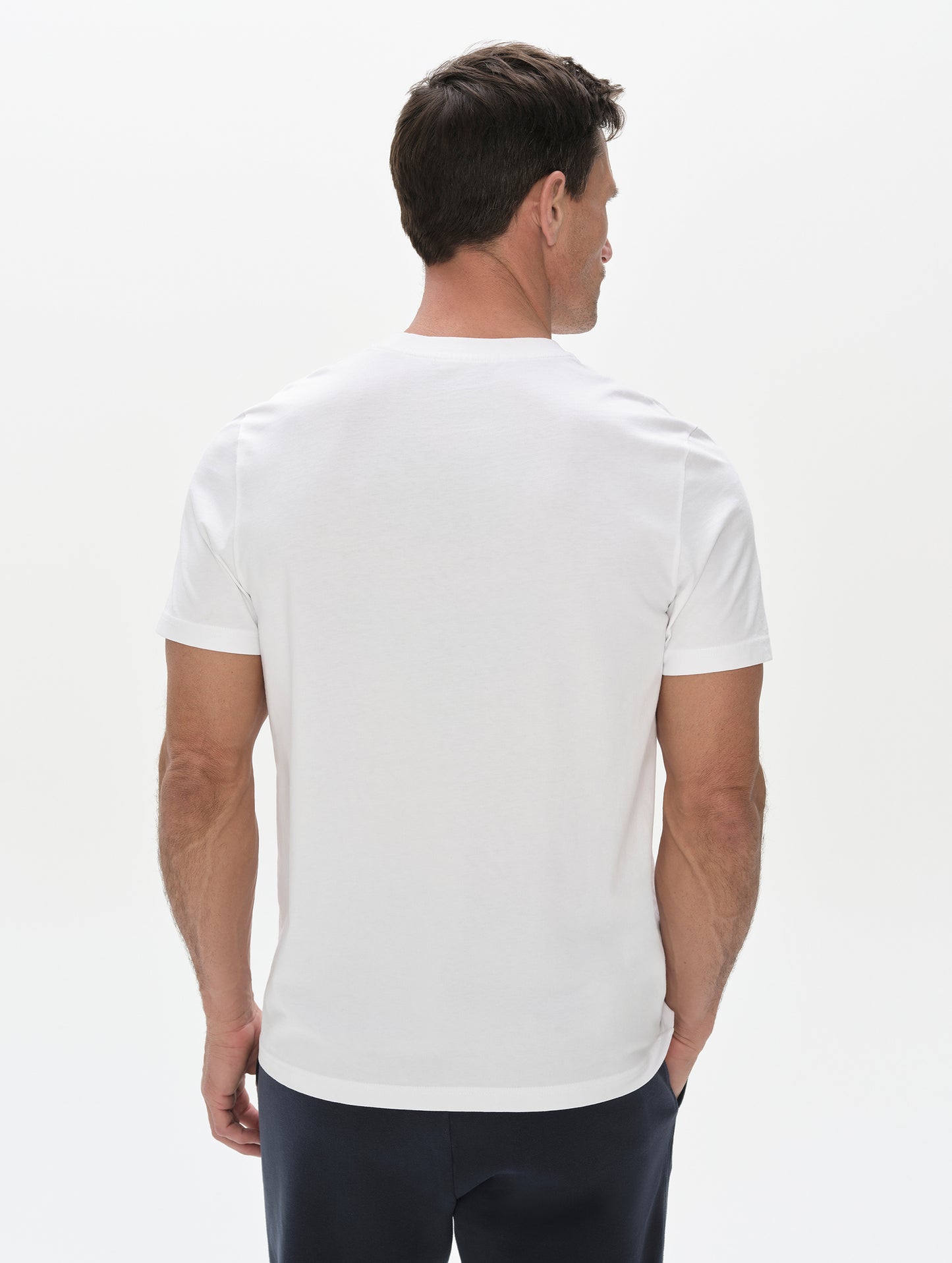 Rear, upper-body view of man wearing the Standard Tee in White from AETHER Apparel.