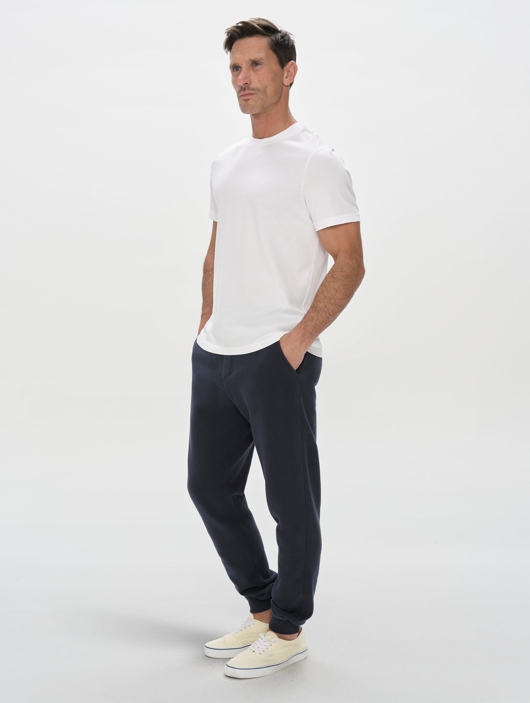 Front, 3/4, full-body view of man wearing the Standard Tee in White from AETHER Apparel.