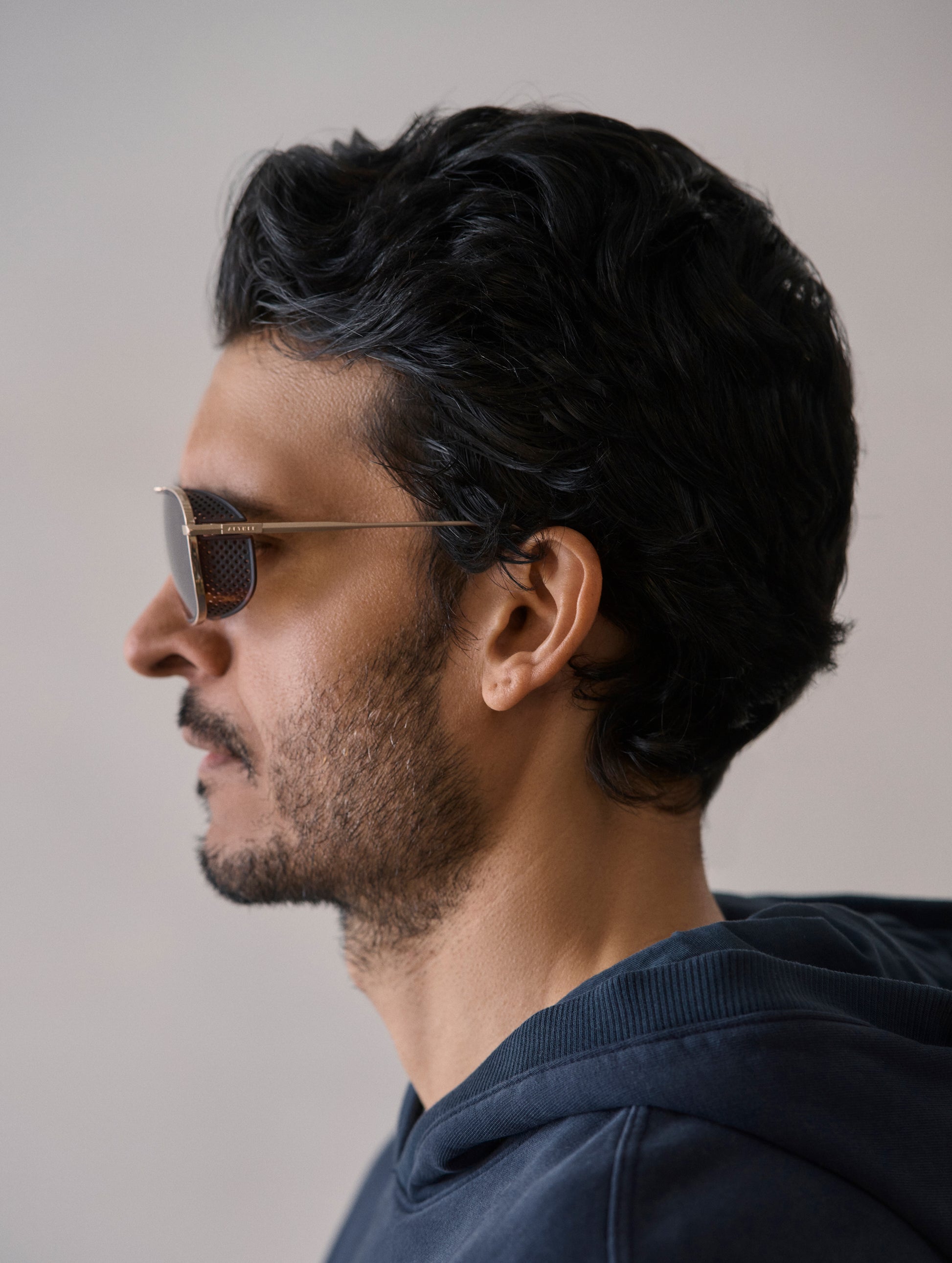 Side profile view of man wearing Summit Sunglass in Brushed Gold titanium with G15 Lens from AETHER Apparel.