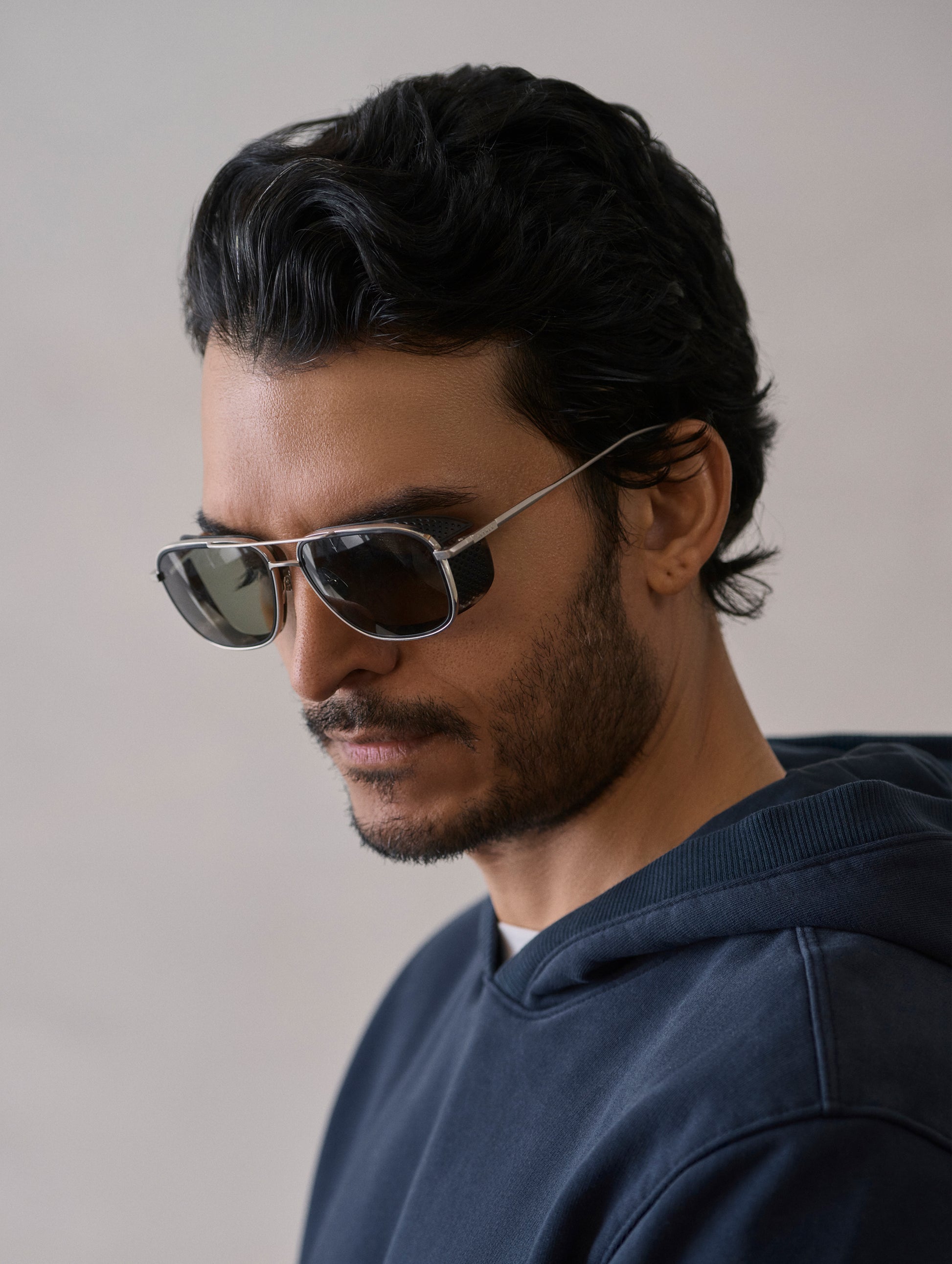 Front 3/4 view of man wearing Summit Sunglass in Brushed Silver titanium with Grey Lens from AETHER Apparel.