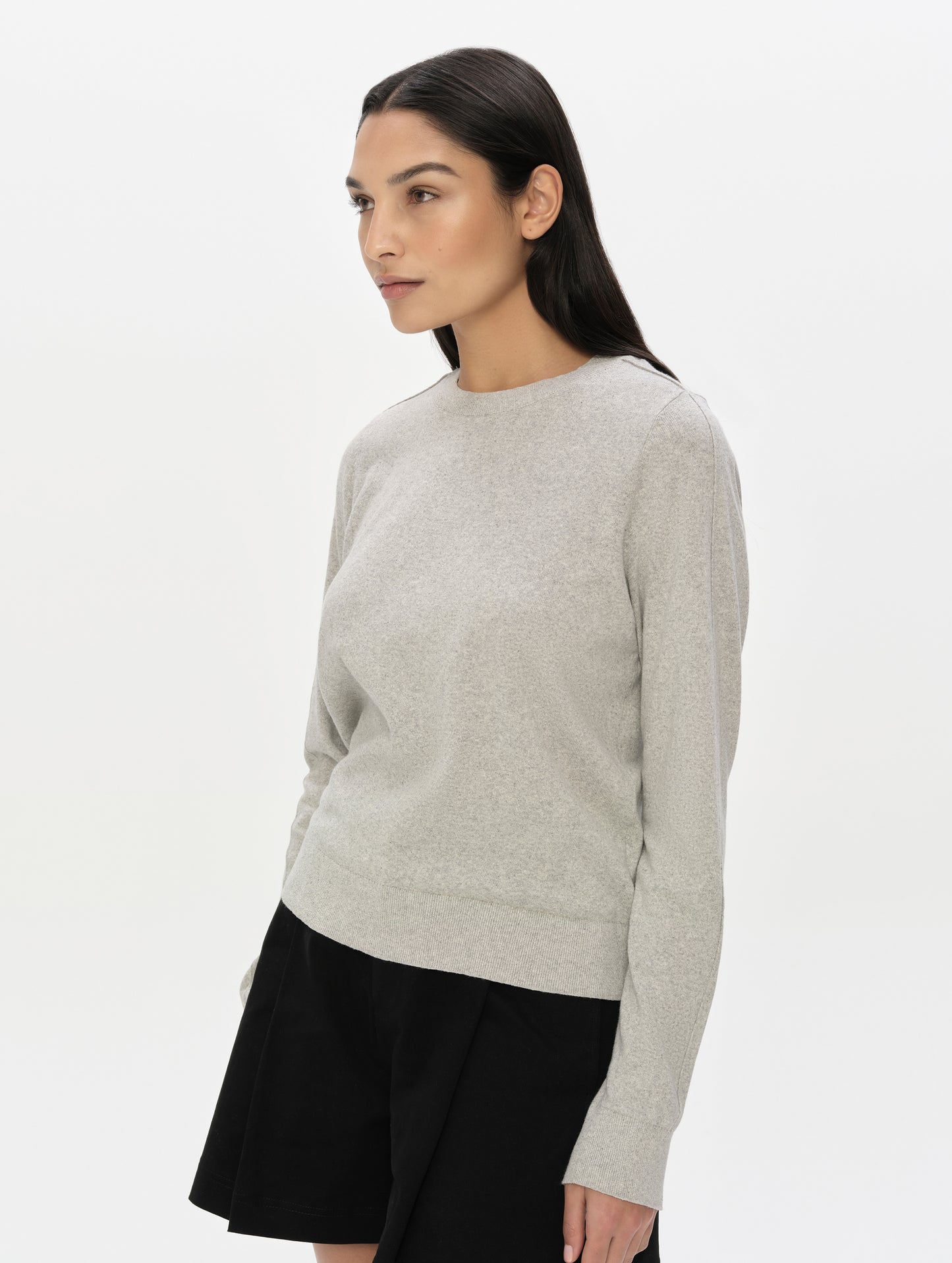 Front, 3/4, upper-body view of woman wearing the Aero Crewneck Sweater 2.0 in Alumino Grey from AETHER Apparel.