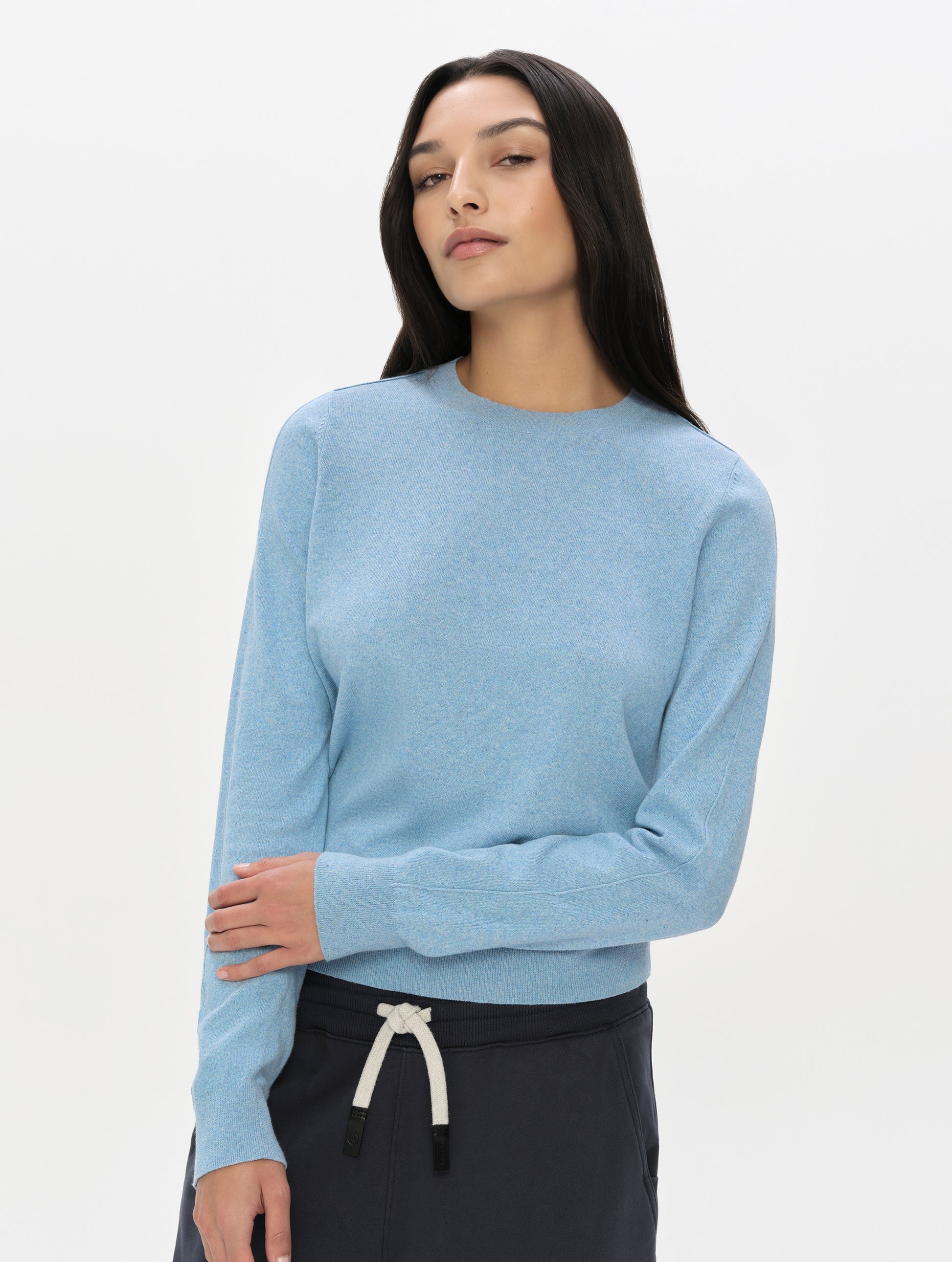 Front, upper-body view of woman wearing the Aero Crewneck Sweater 2.0 in Cloud Blue from AETHER Apparel.