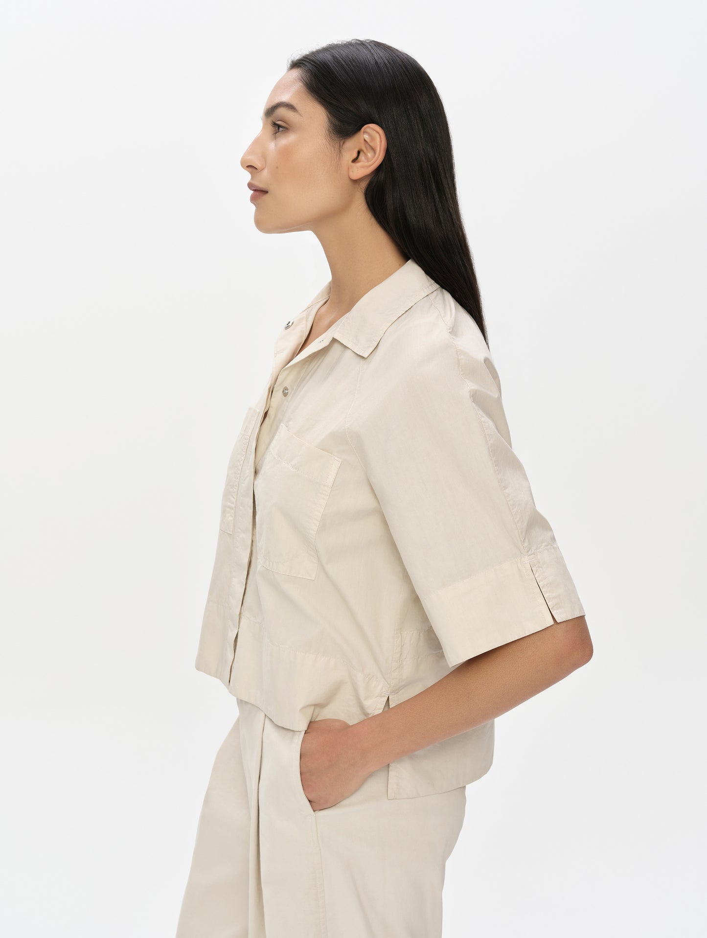 Side, profile, upper body view of woman wearing the Alice Shirt in Bone from AETHER Apparel.