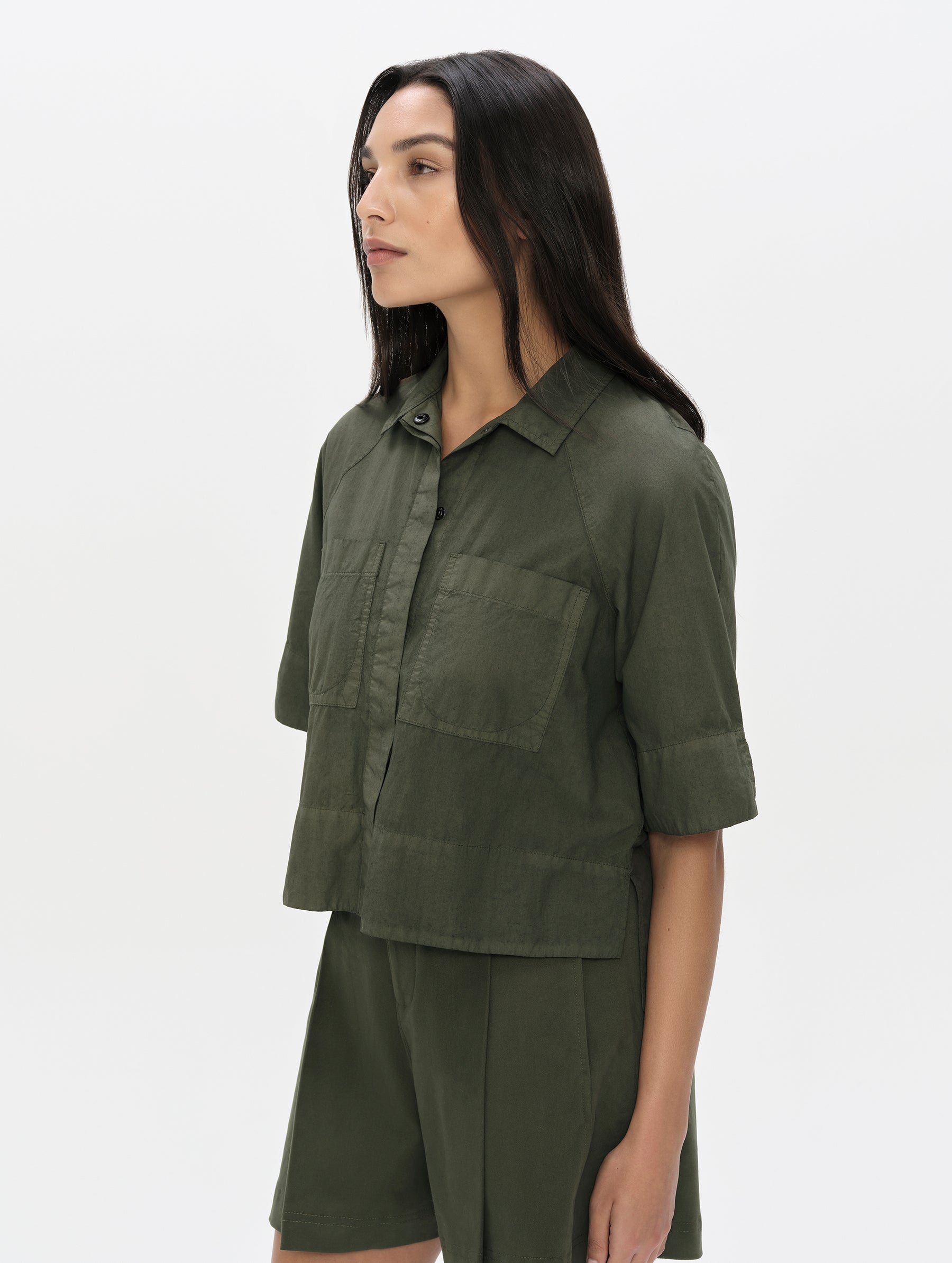 Front, 3/4 upper body view of woman wearing the Alice Shirt in Forest Green from AETHER Apparel.