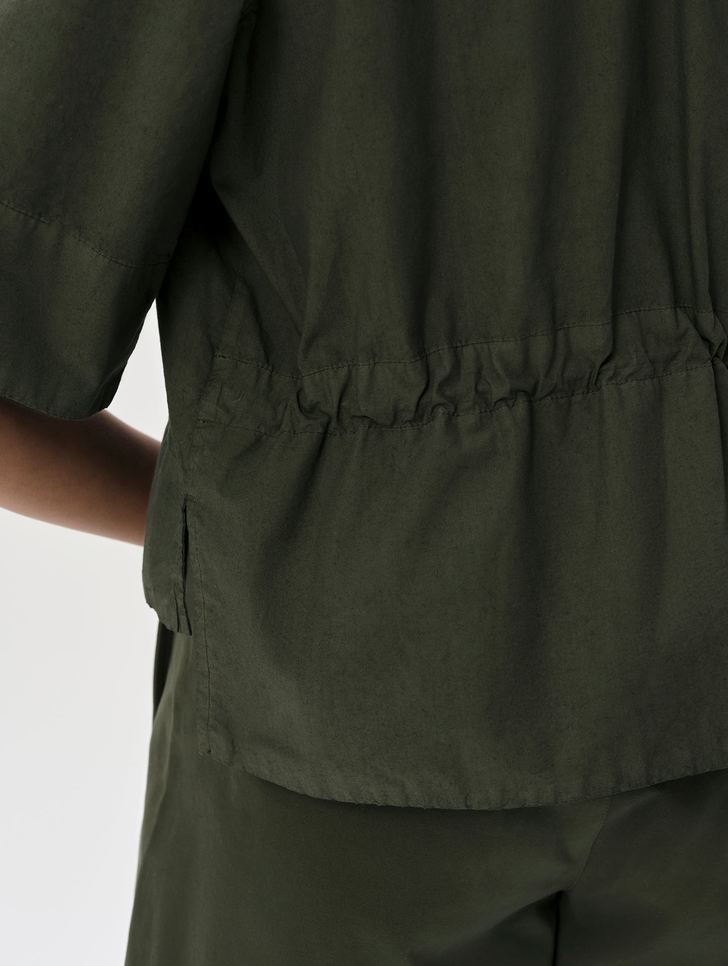 Closeup detailed view of the internal bungee cord cinch at the back waist of the Alice Shirt in Forest Green from AETHER Apparel.
