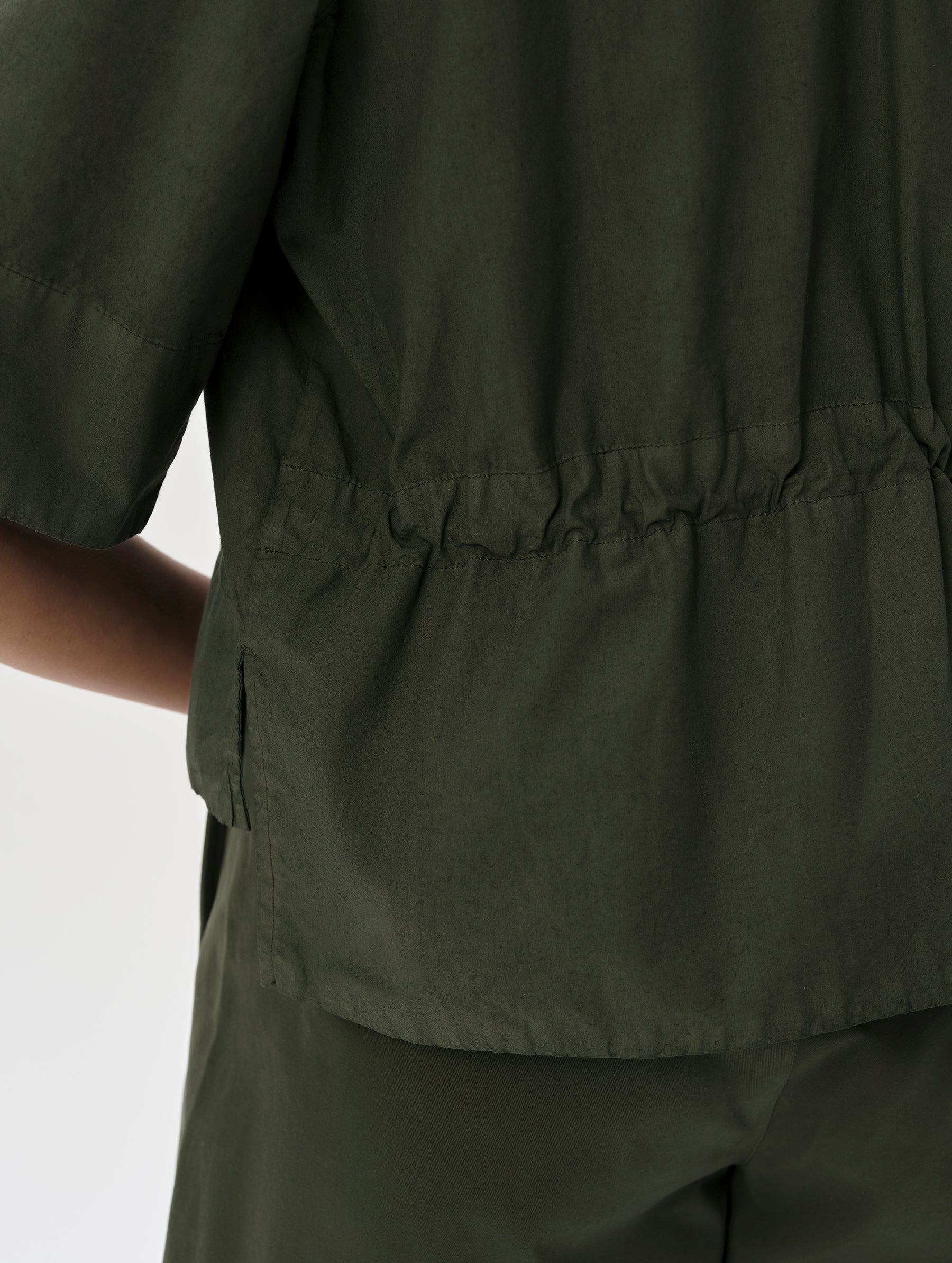 Closeup detailed view of the internal bungee cord cinch at the back waist of the Alice Shirt in Forest Green from AETHER Apparel.
