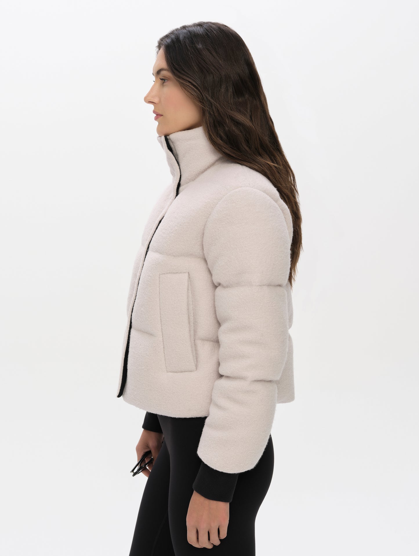 Side profile upper-body view of woman wearing the Aura Puffer Jacket Wool in Bone white from AETHER Apparel.