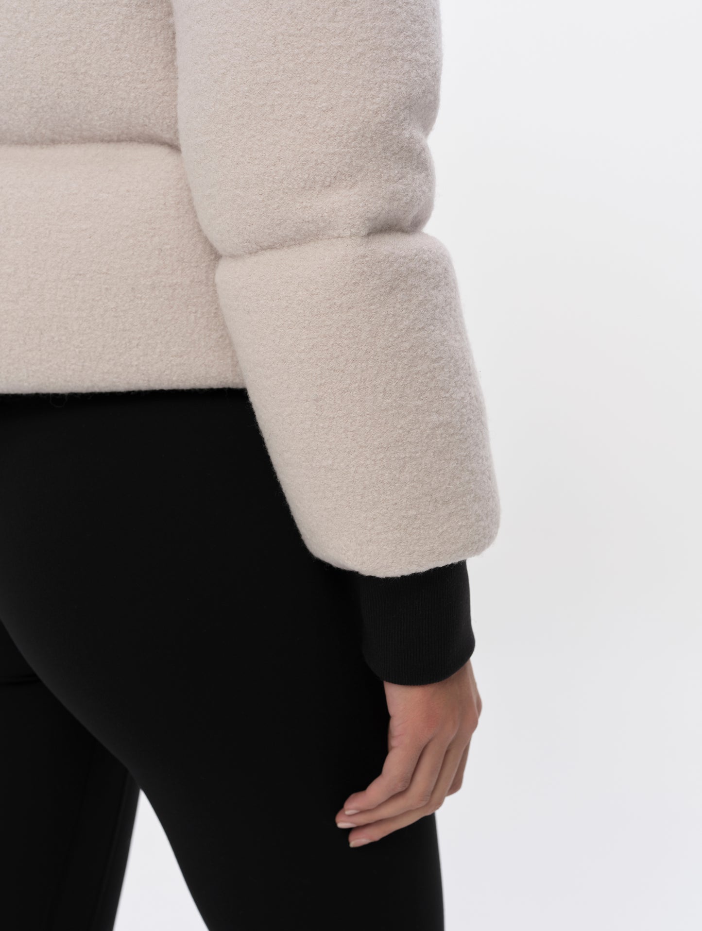 Closeup detailed view of the rib-knit cuffs and hem on the Aura Puffer Jacket Wool in Bone white from AETHER Apparel.
