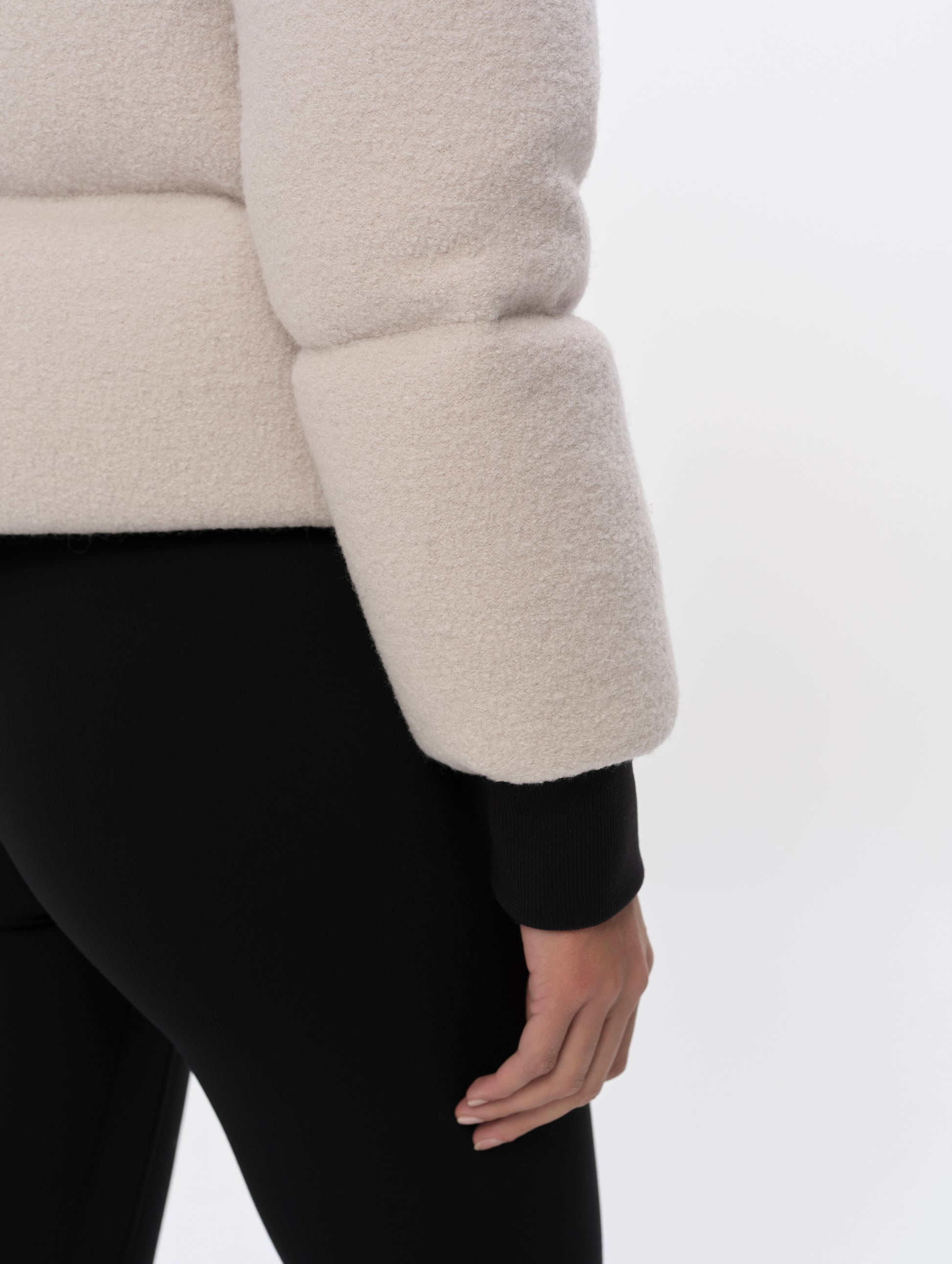 Closeup detailed view of the rib-knit cuffs and hem on the Aura Puffer Jacket Wool in Bone white from AETHER Apparel.