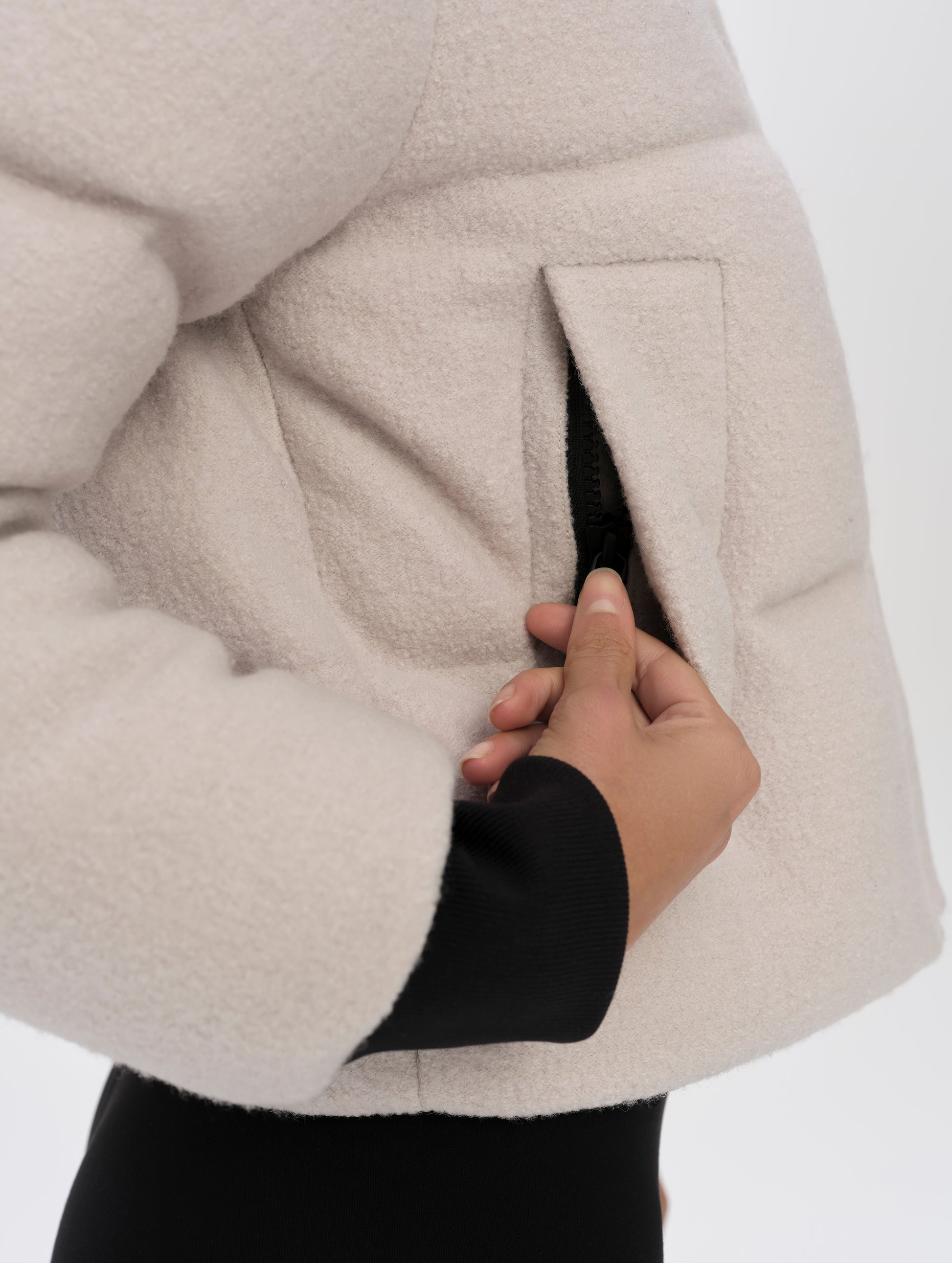 Closeup detailed view of the zipper-secured hand pockets on the Aura Puffer Jacket Wool in Bone white from AETHER Apparel.