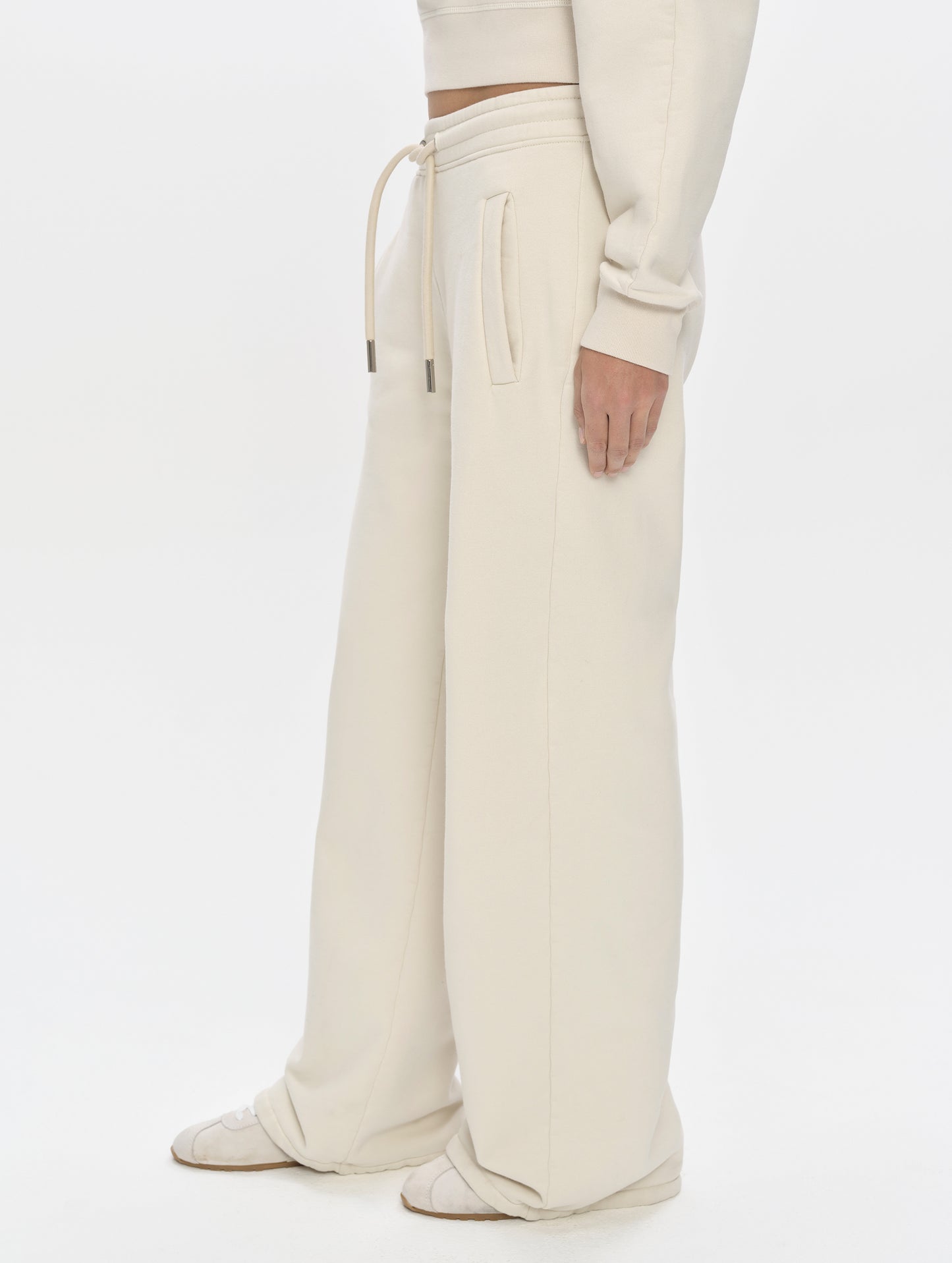 Side profile, lower-body view of woman wearing the Ayla Wide-Leg Sweatpant in Bone from AETHER Apparel.