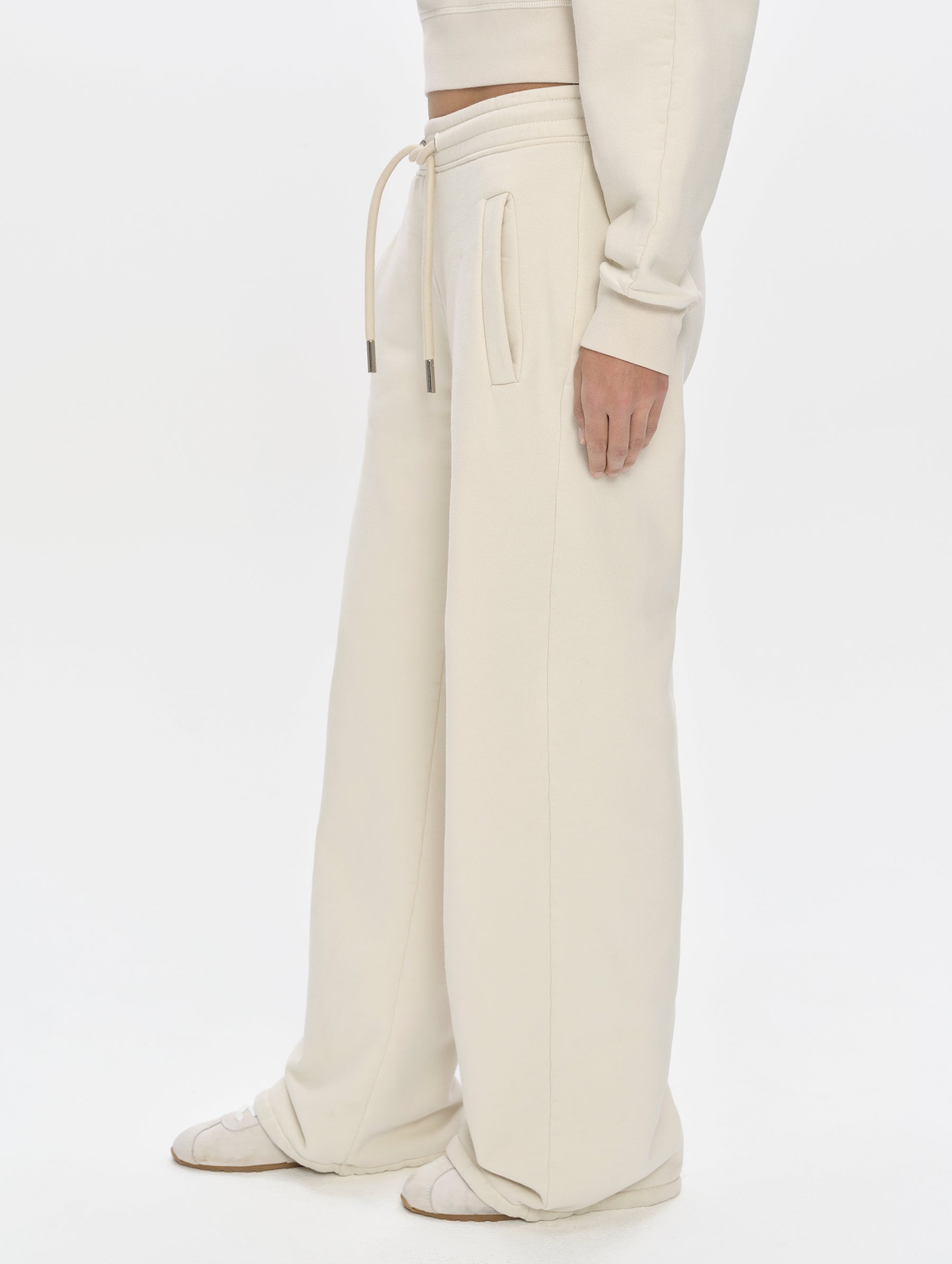 Side profile, lower-body view of woman wearing the Ayla Wide-Leg Sweatpant in Bone from AETHER Apparel.