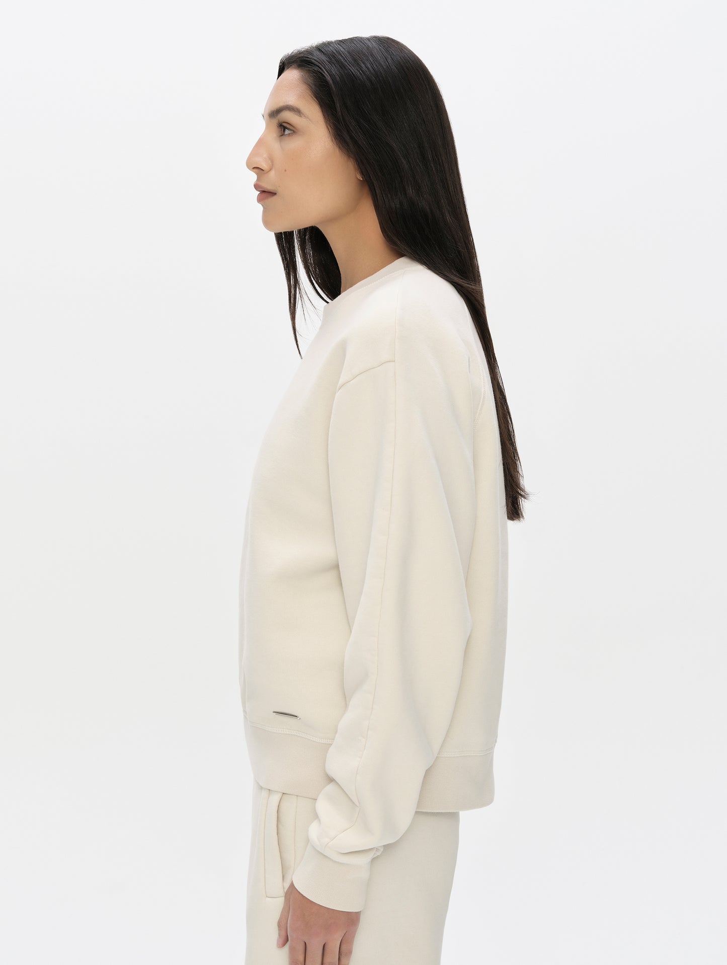 Side profile, upper-body view of woman wearing the Ayla Crewneck Sweatshirt in Bone from AETHER Apparel.