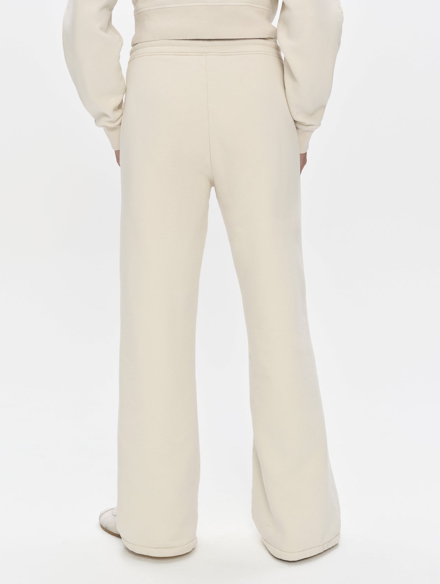 Rear, lower-body view of woman wearing the Ayla Wide-Leg Sweatpant in Bone from AETHER Apparel.