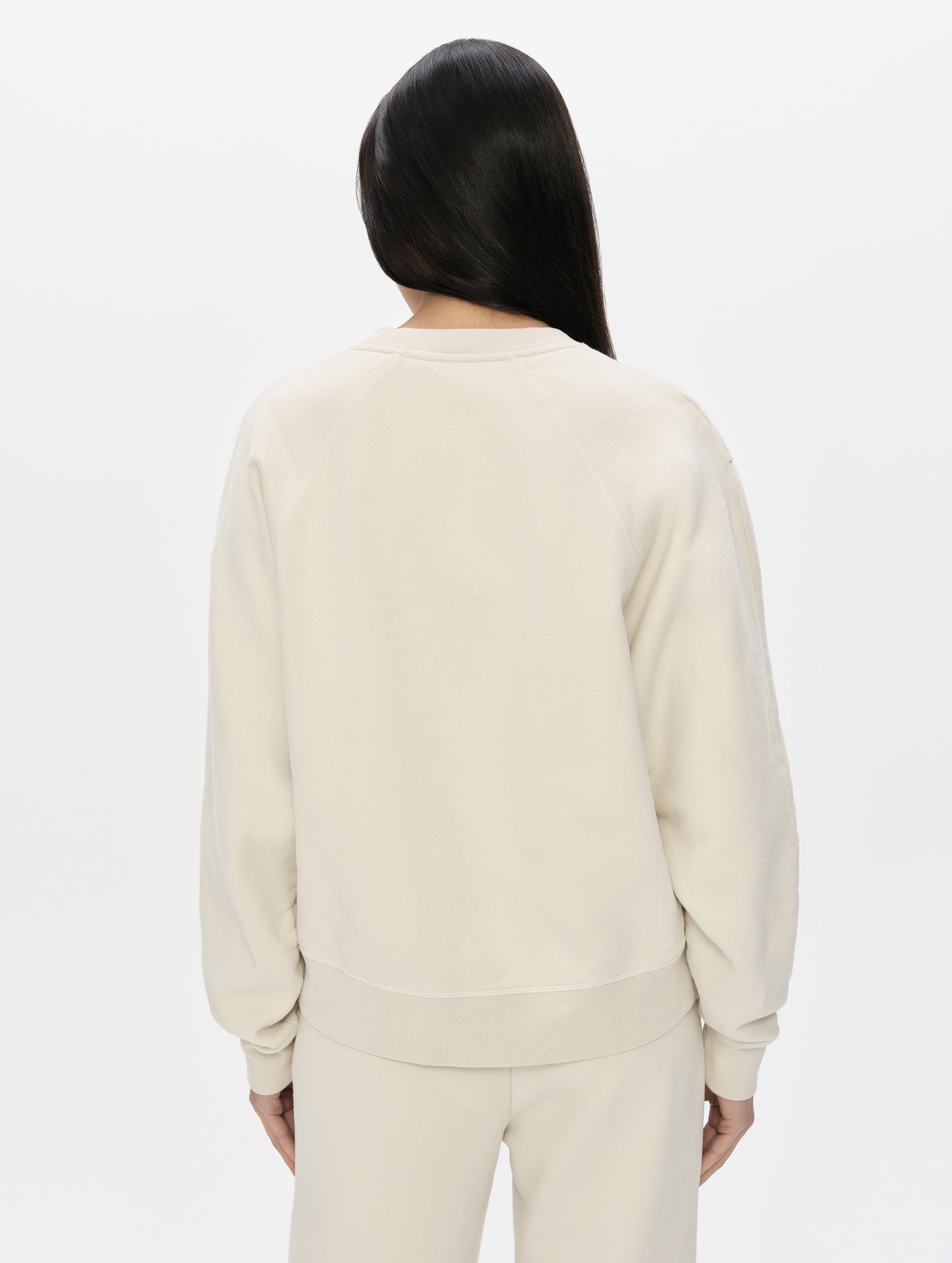 Rear, upper-body view of woman wearing the Ayla Crewneck Sweatshirt in Bone from AETHER Apparel.