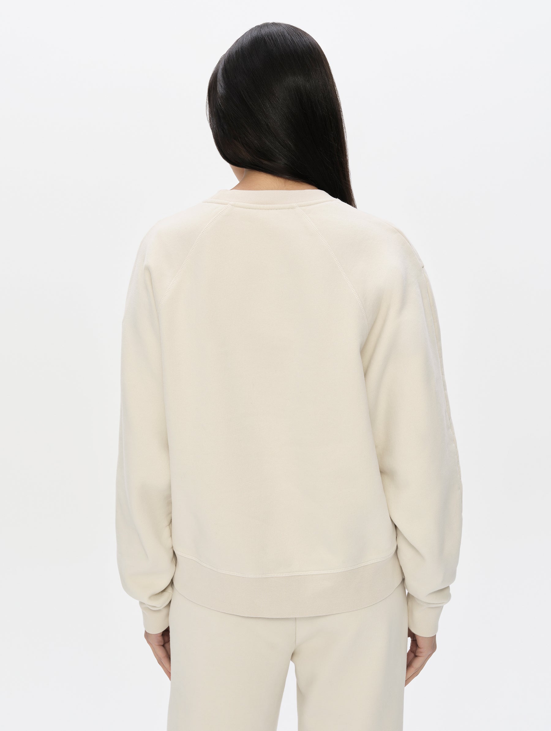 Rear, upper-body view of woman wearing the Ayla Crewneck Sweatshirt in Bone from AETHER Apparel.