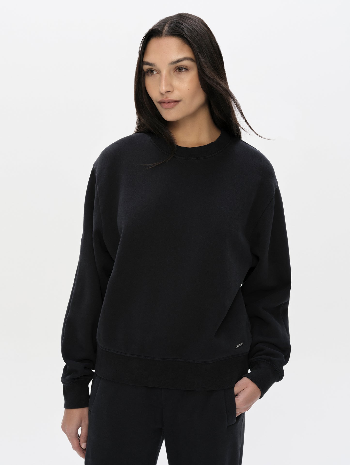 Front, upper-body view of woman wearing the Ayla Crewneck Sweatshirt in Onyx Black from AETHER Apparel.