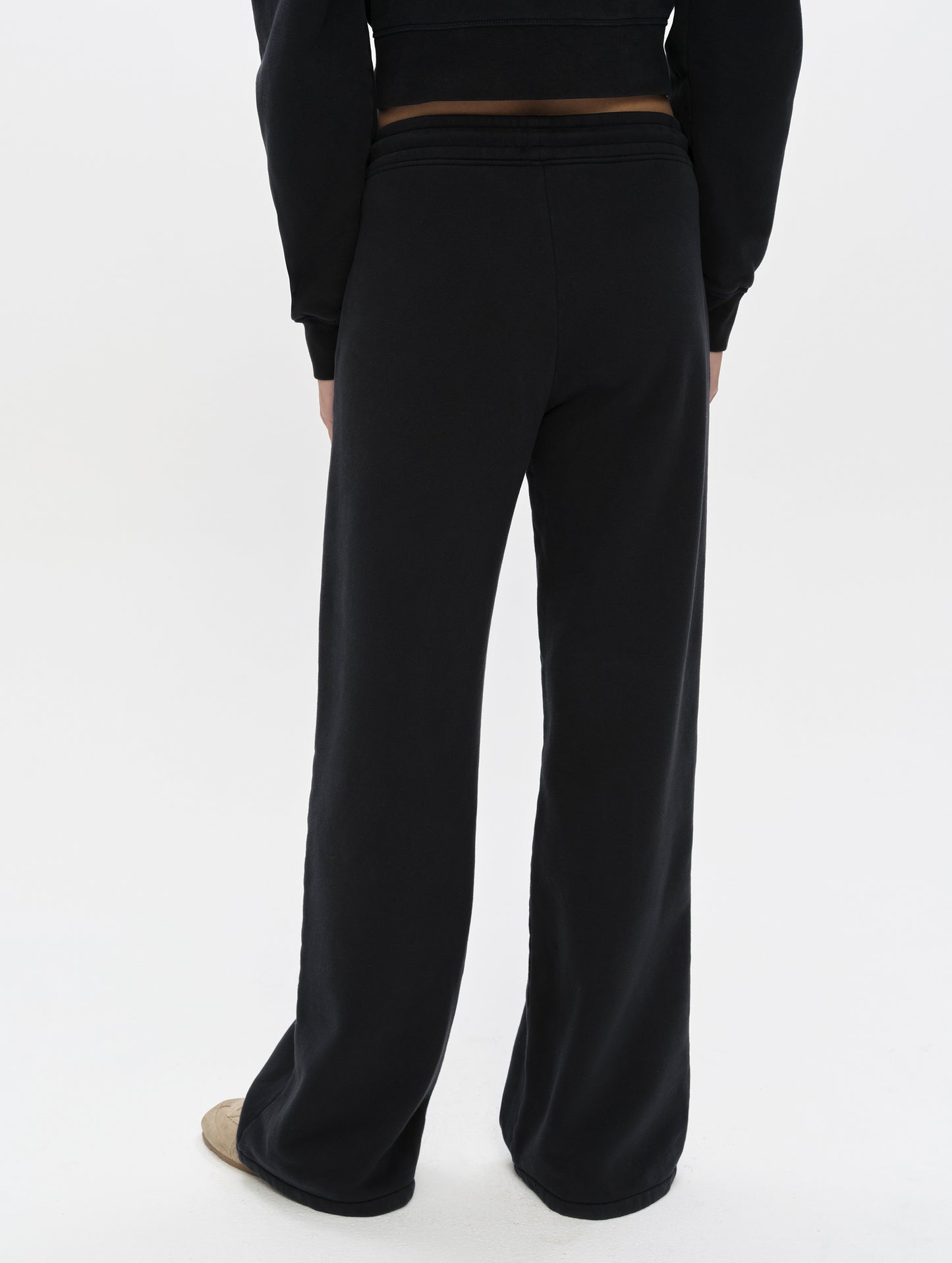 Rear, lower-body view of woman wearing the Ayla Wide-Leg Sweatpant in Onyx Black from AETHER Apparel.