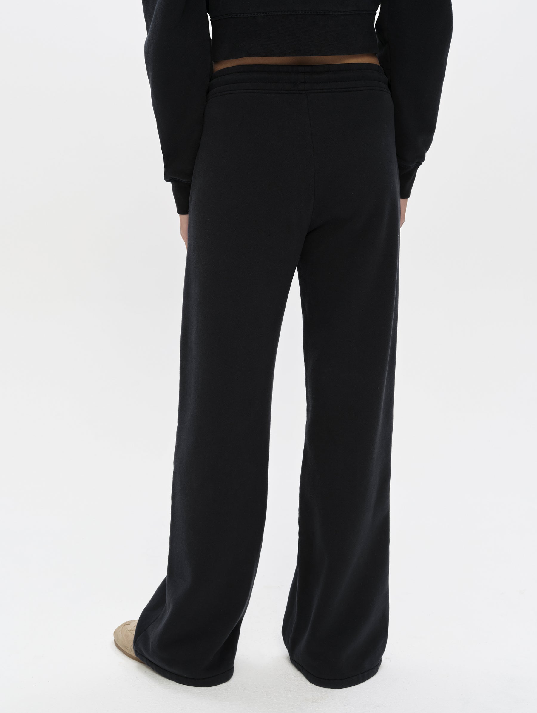 Rear, lower-body view of woman wearing the Ayla Wide-Leg Sweatpant in Onyx Black from AETHER Apparel.