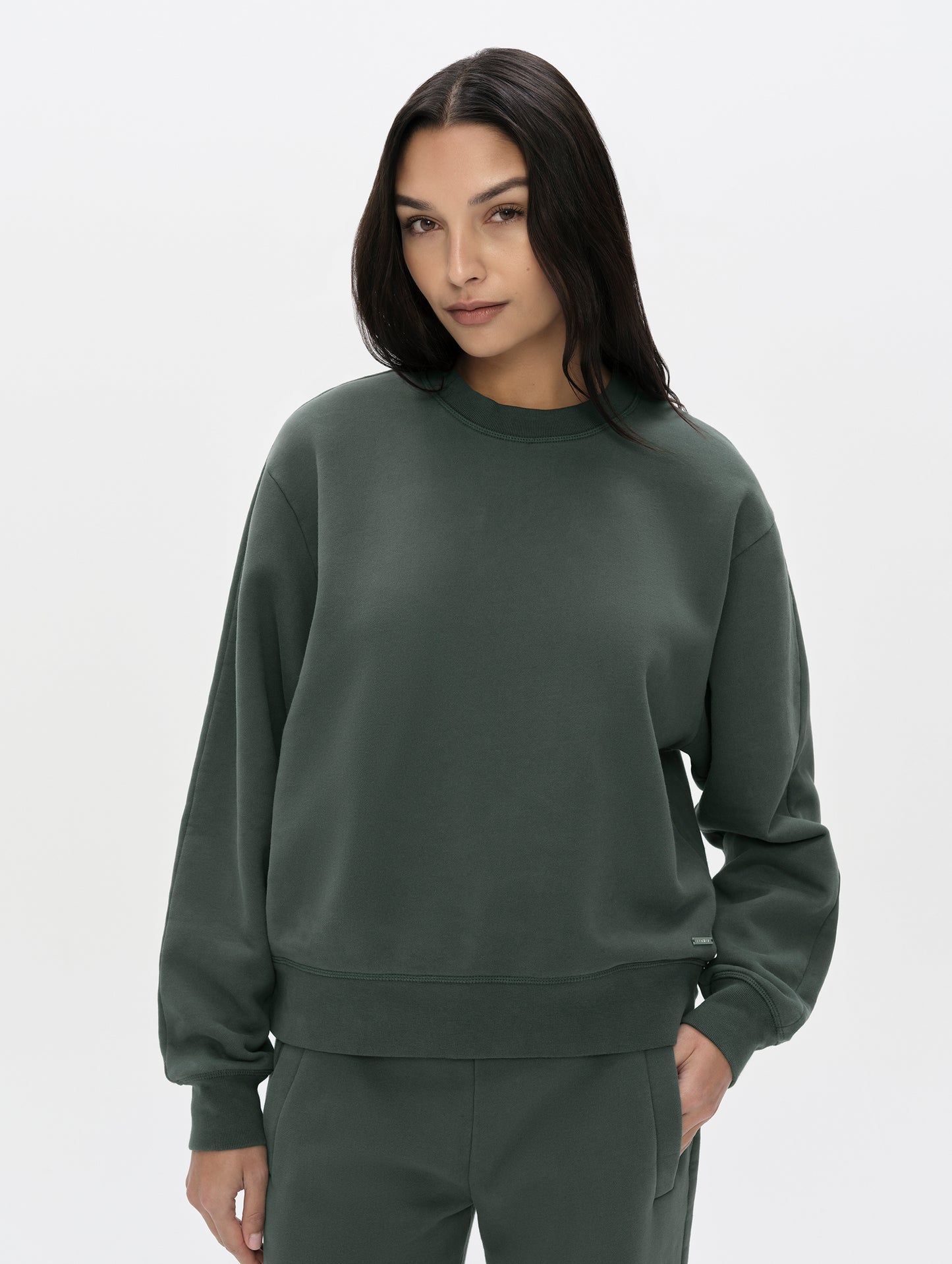 Front, upper-body view of woman wearing the Ayla Crewneck Sweatshirt in Saville Green from AETHER Apparel.