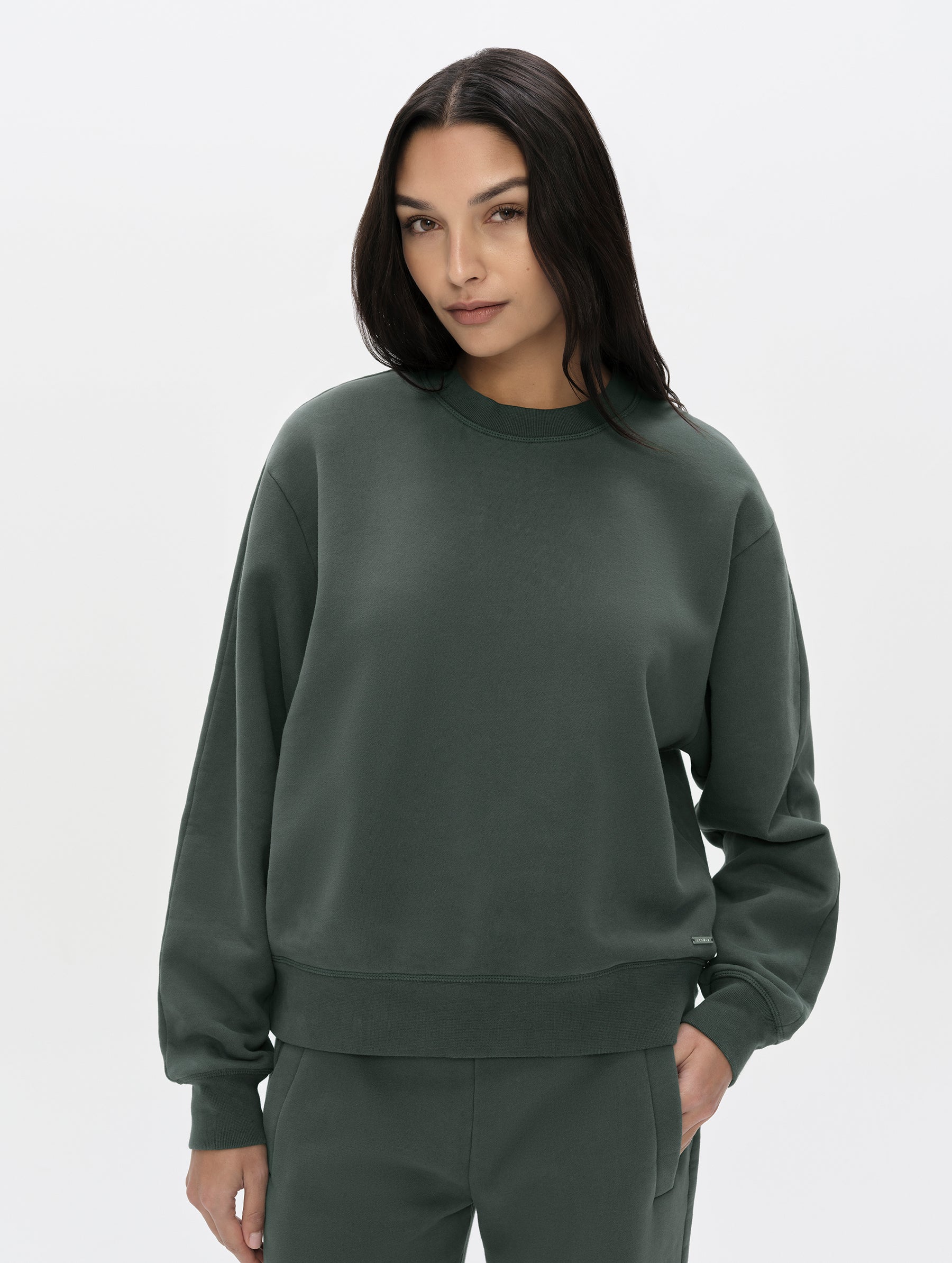 Front, upper-body view of woman wearing the Ayla Crewneck Sweatshirt in Saville Green from AETHER Apparel.