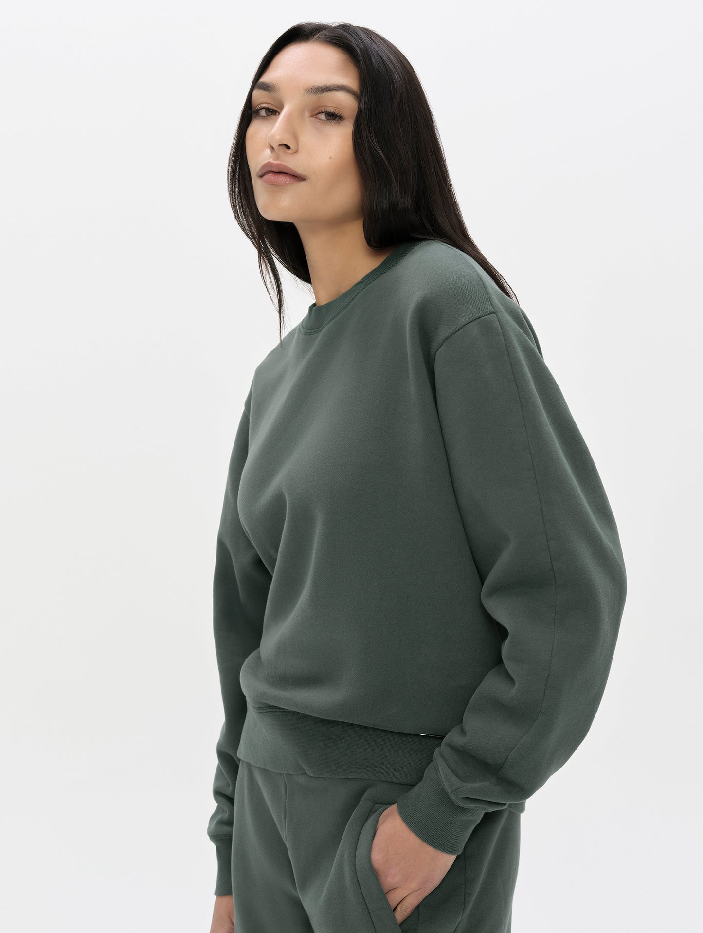 Front, 3/4, upper-body view of woman wearing the Ayla Crewneck Sweatshirt in Saville Green from AETHER Apparel.