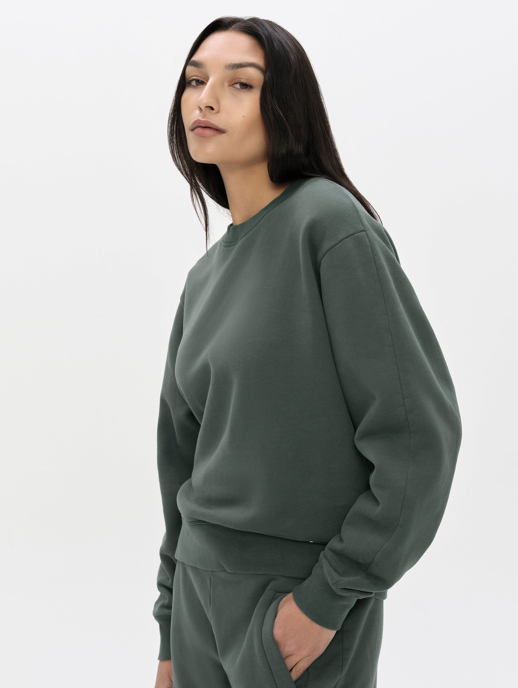 Front, 3/4, upper-body view of woman wearing the Ayla Crewneck Sweatshirt in Saville Green from AETHER Apparel.