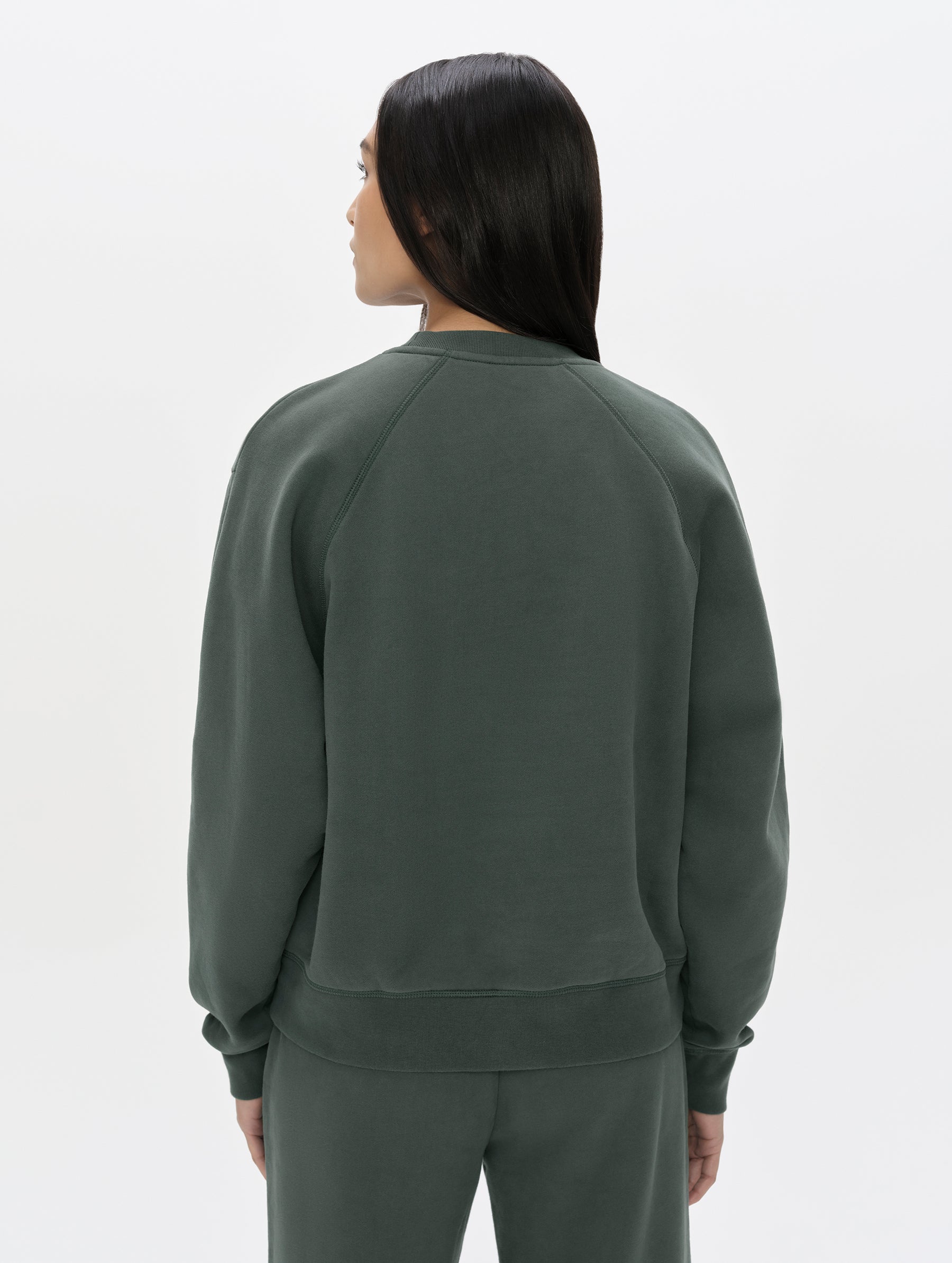Rear, upper-body view of woman wearing the Ayla Crewneck Sweatshirt in Saville Green from AETHER Apparel.