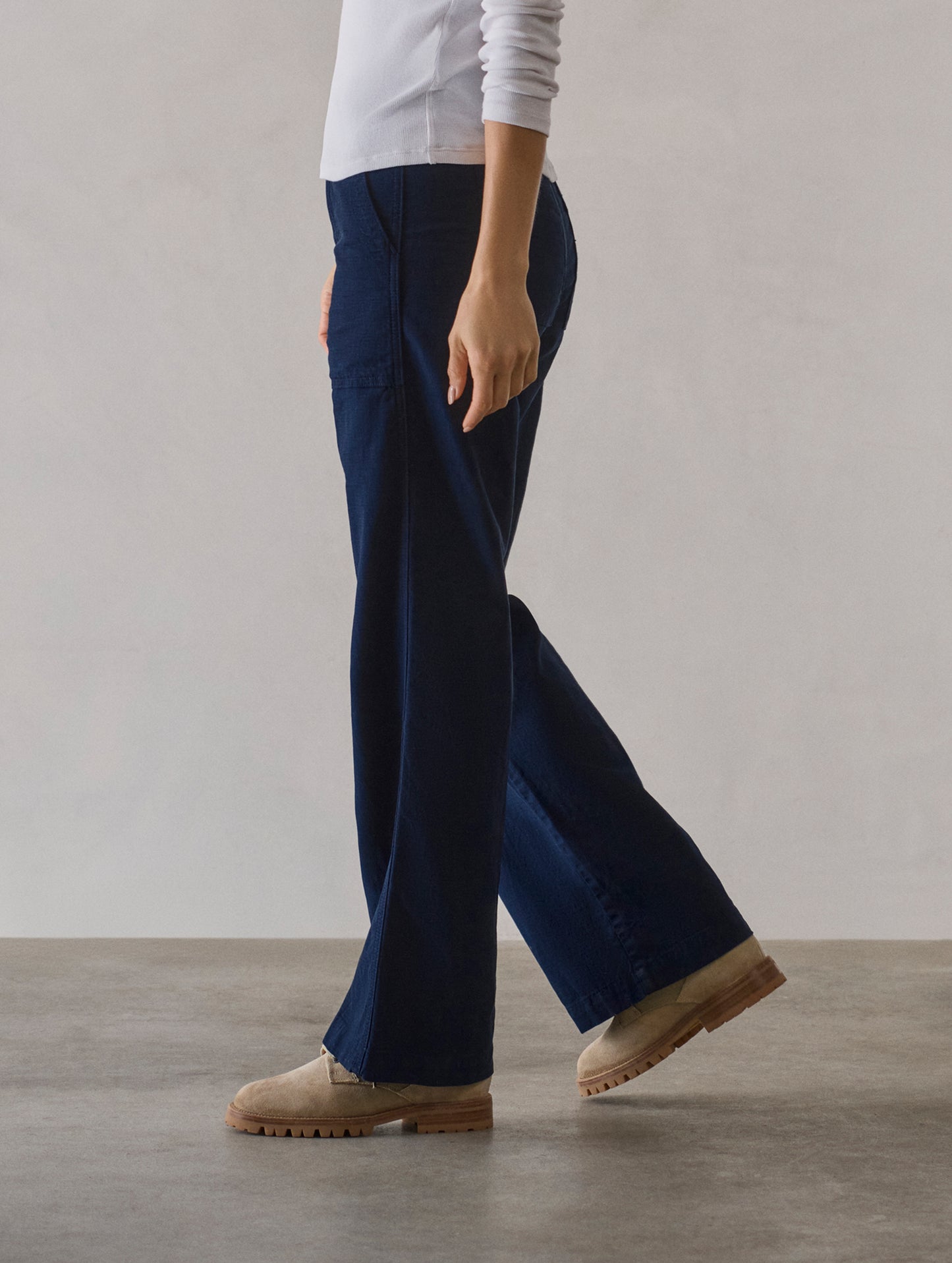 Side profile lower body view of woman wearing Bella Travel Pant in Nordic Navy from AETHER Apparel.