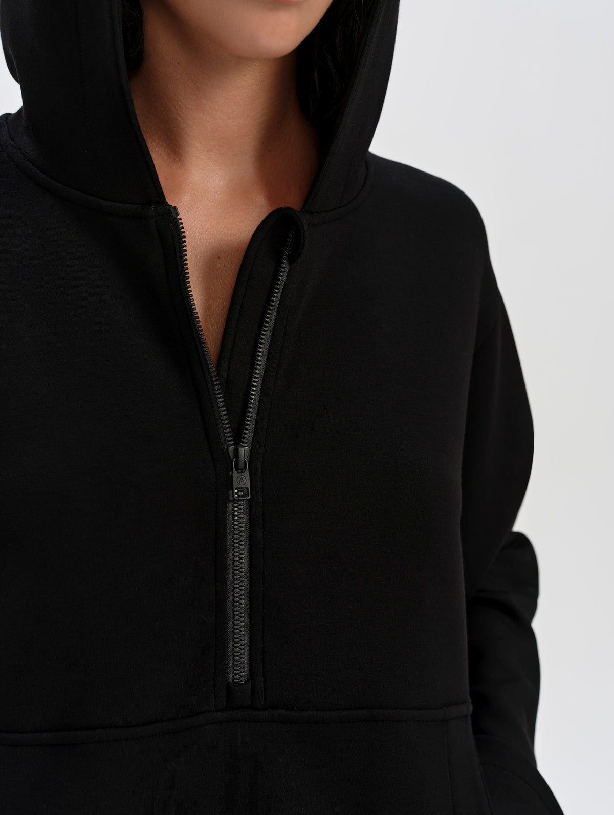 Front upper-body view of woman wearing the Blaire Premium Hoodie in Onyx Black from AETHER Apparel with the center-front zipper half-open. 