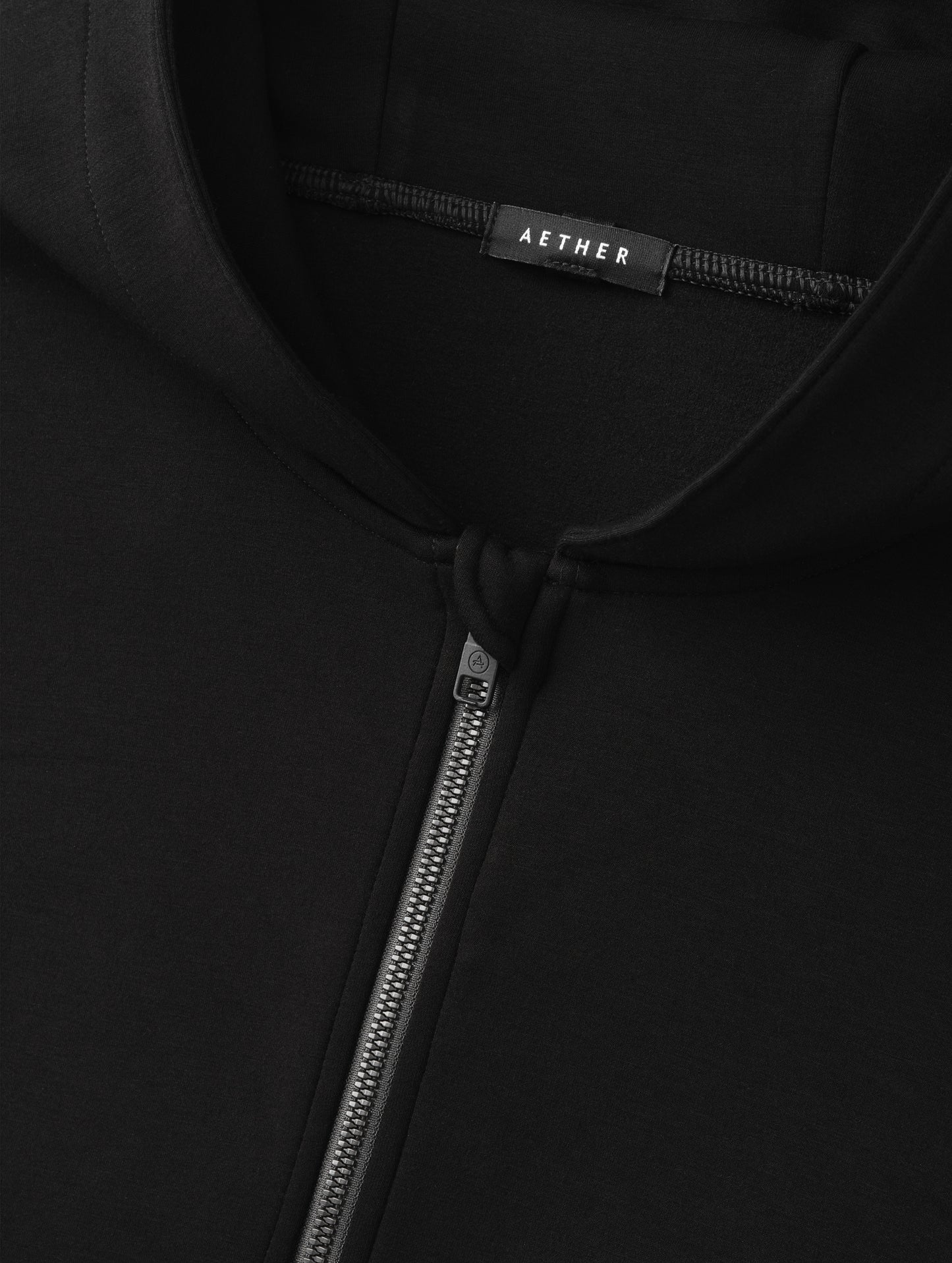Closeup detailed view of the center-front zipper on the Blaire Premium Hoodie in Onyx Black from AETHER Apparel.