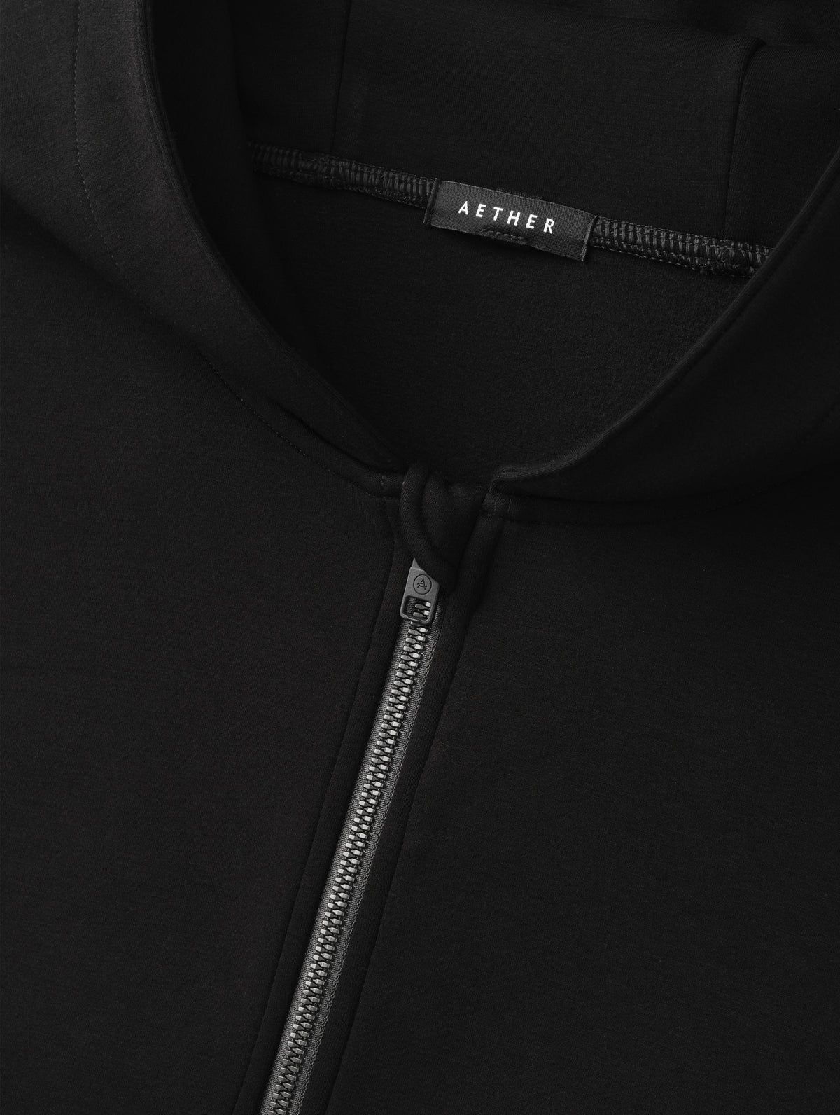 Closeup detailed view of the center-front zipper on the Blaire Premium Hoodie in Onyx Black from AETHER Apparel.