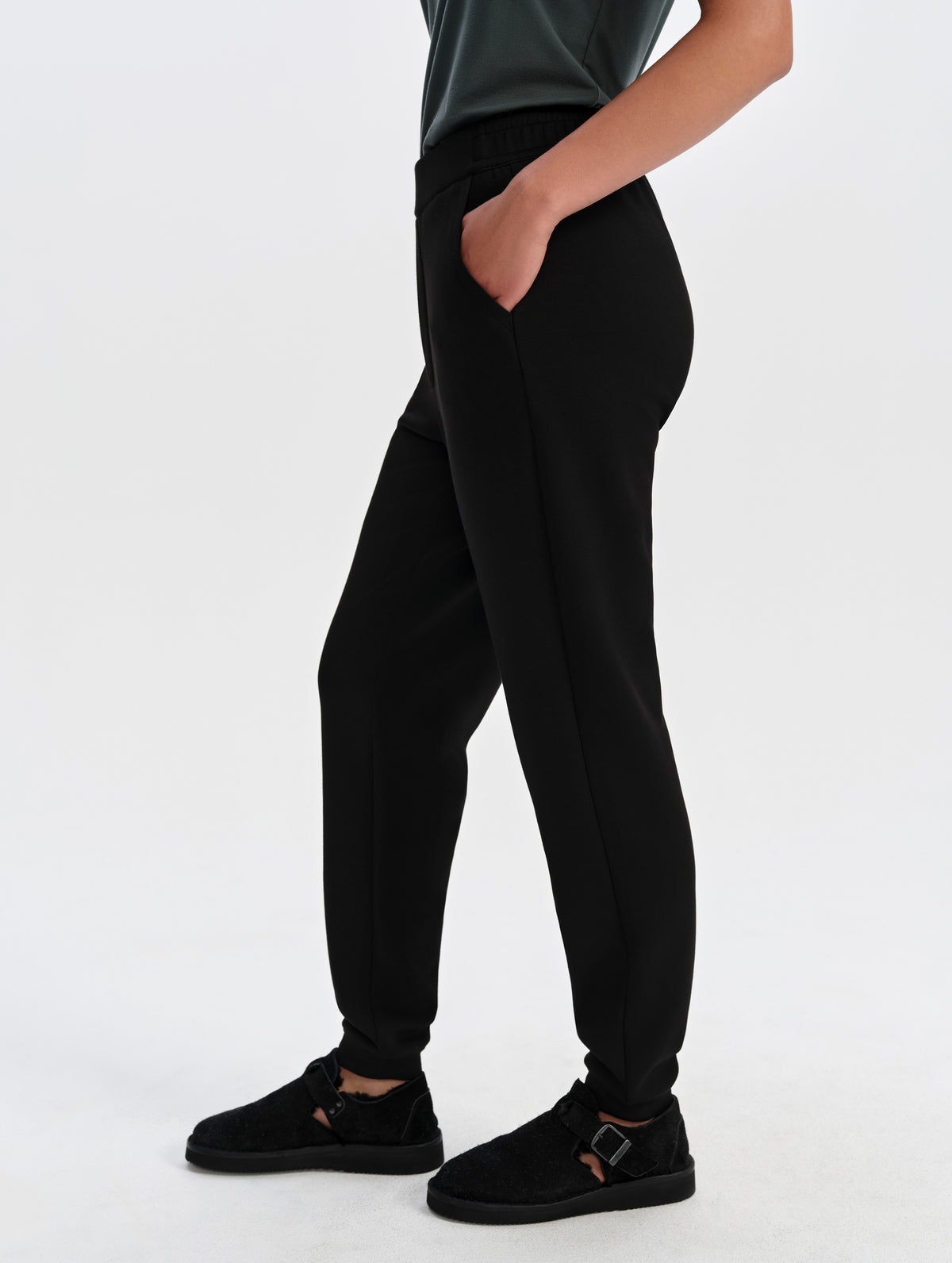 Side profile lower-body view of woman wearing the Blaire Premium Sweatpant in Onyx Black from AETHER Apparel.