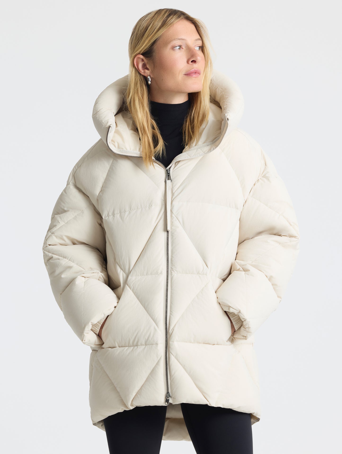 Front upper-body view of woman with hood down wearing the Callie Oversized Down Parka in Bone from AETHER Apparel.