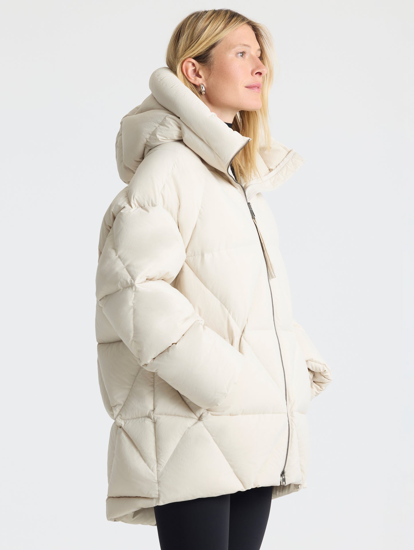Side profile upper-body view of woman wearing the Callie Oversized Down Parka in Bone from AETHER Apparel.