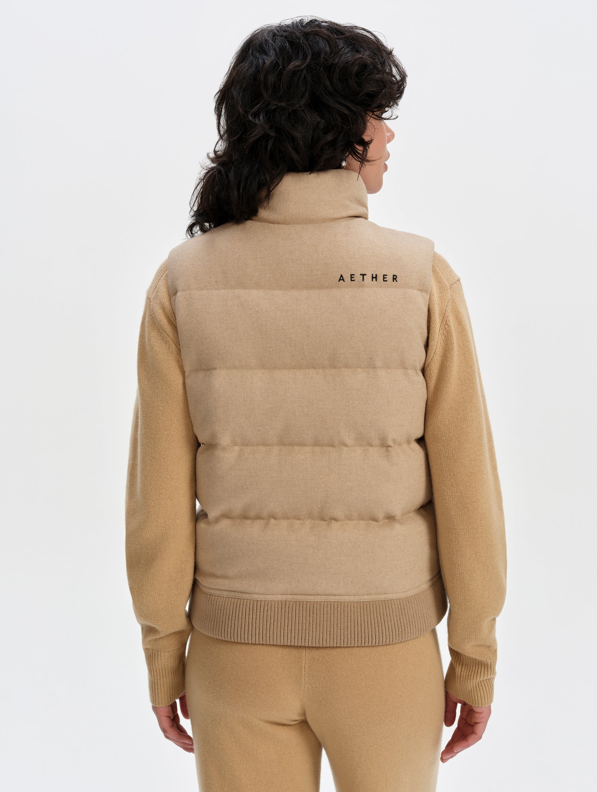 Rear upper-body view of woman wearing Channing Vest 2.0 in Latte Brown from AETHER Apparel.