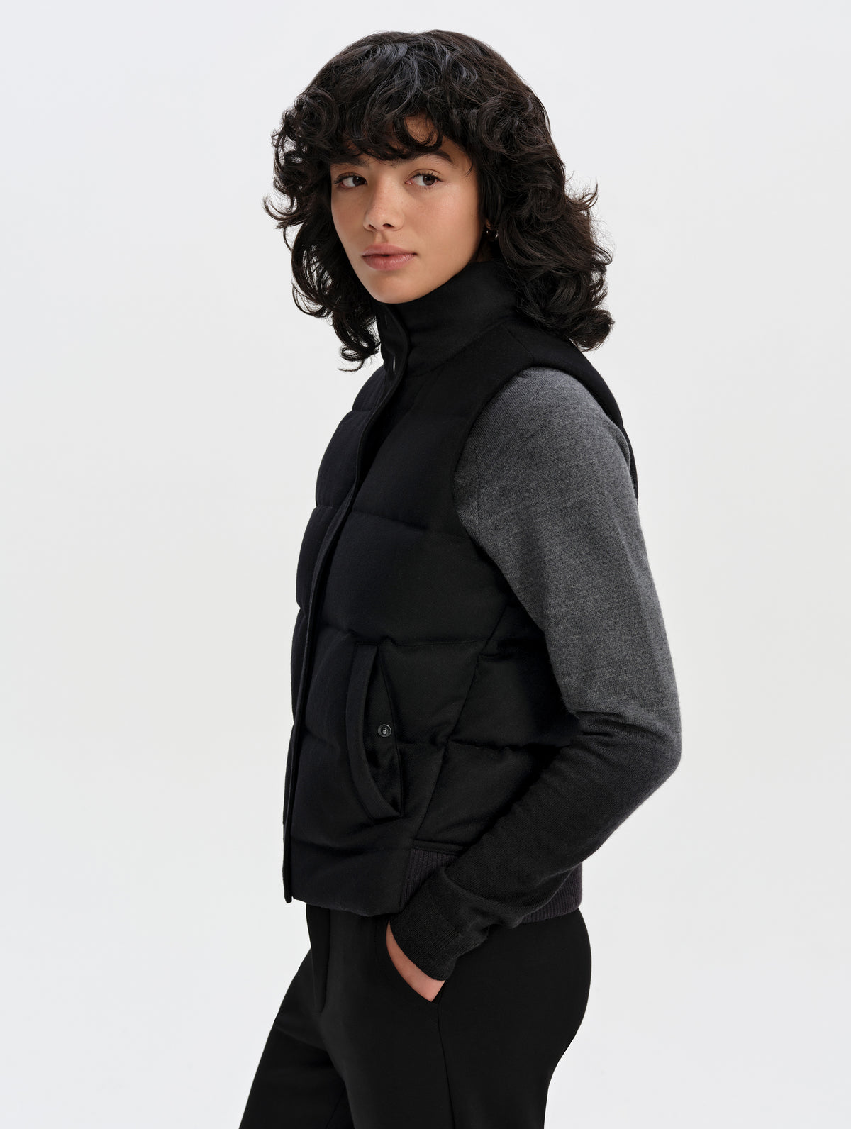 Side profile upper-body view of woman wearing Channing Vest 2.0 in Onyx Black from AETHER Apparel.