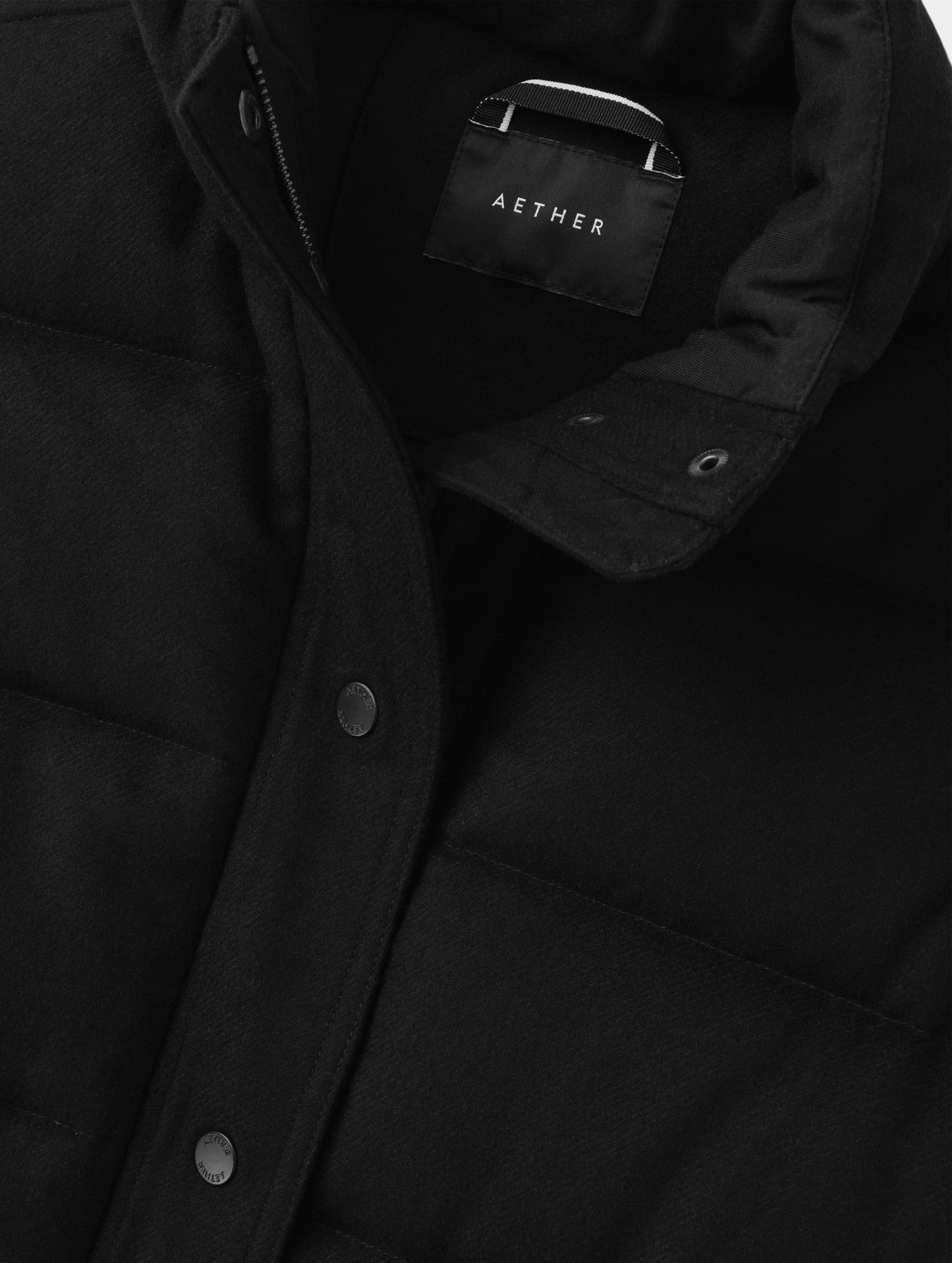 Closeup detailed view of the main center-front snap closure on the Channing Vest 2.0 in Onyx Black from AETHER Apparel.